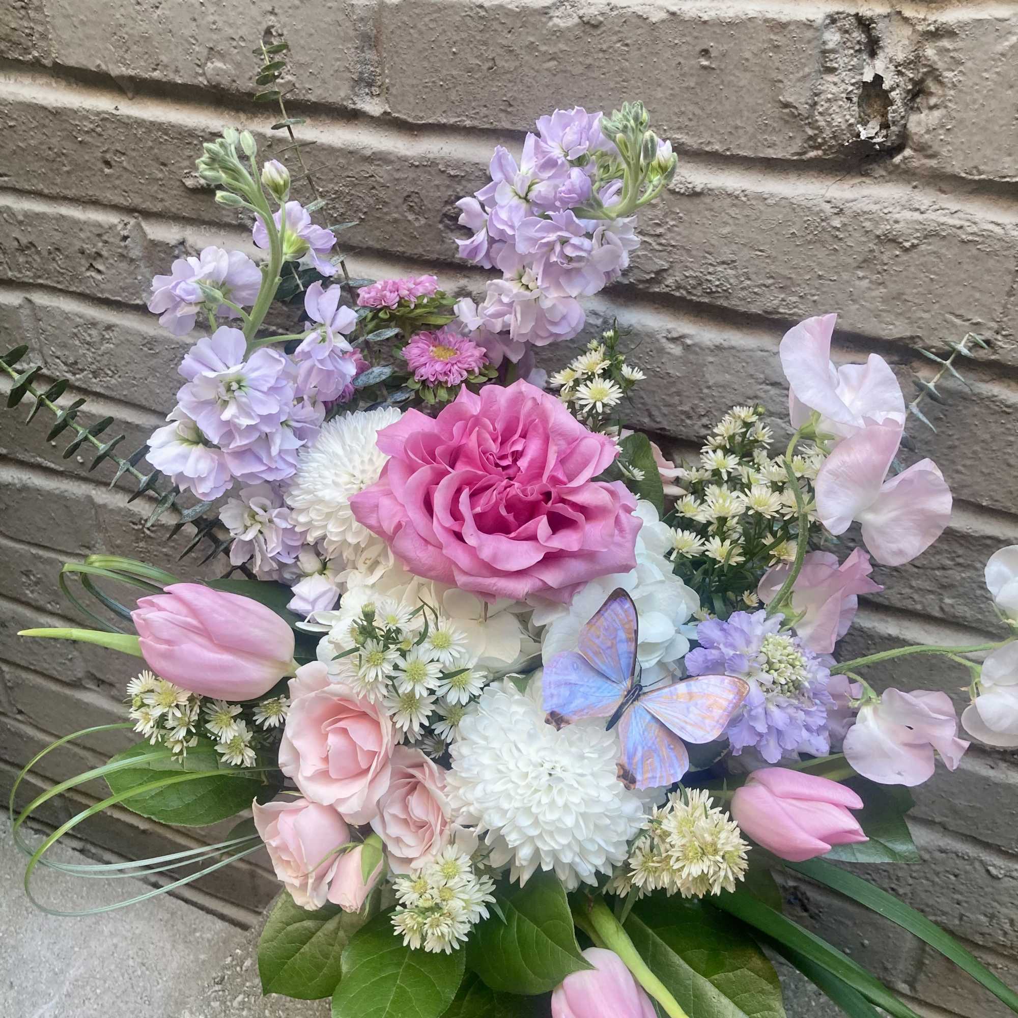 Pink and lavender bouquet with roses, tulips, and a butterfly accent