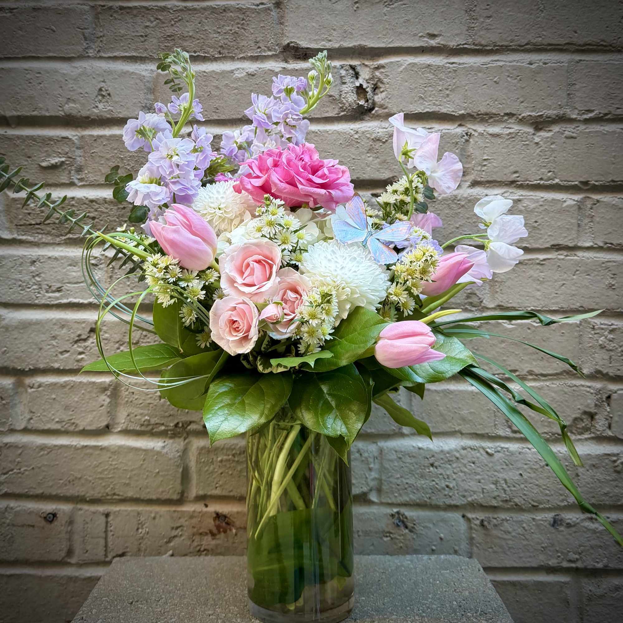 Pink and lavender flowers arranged in a clear glass vase