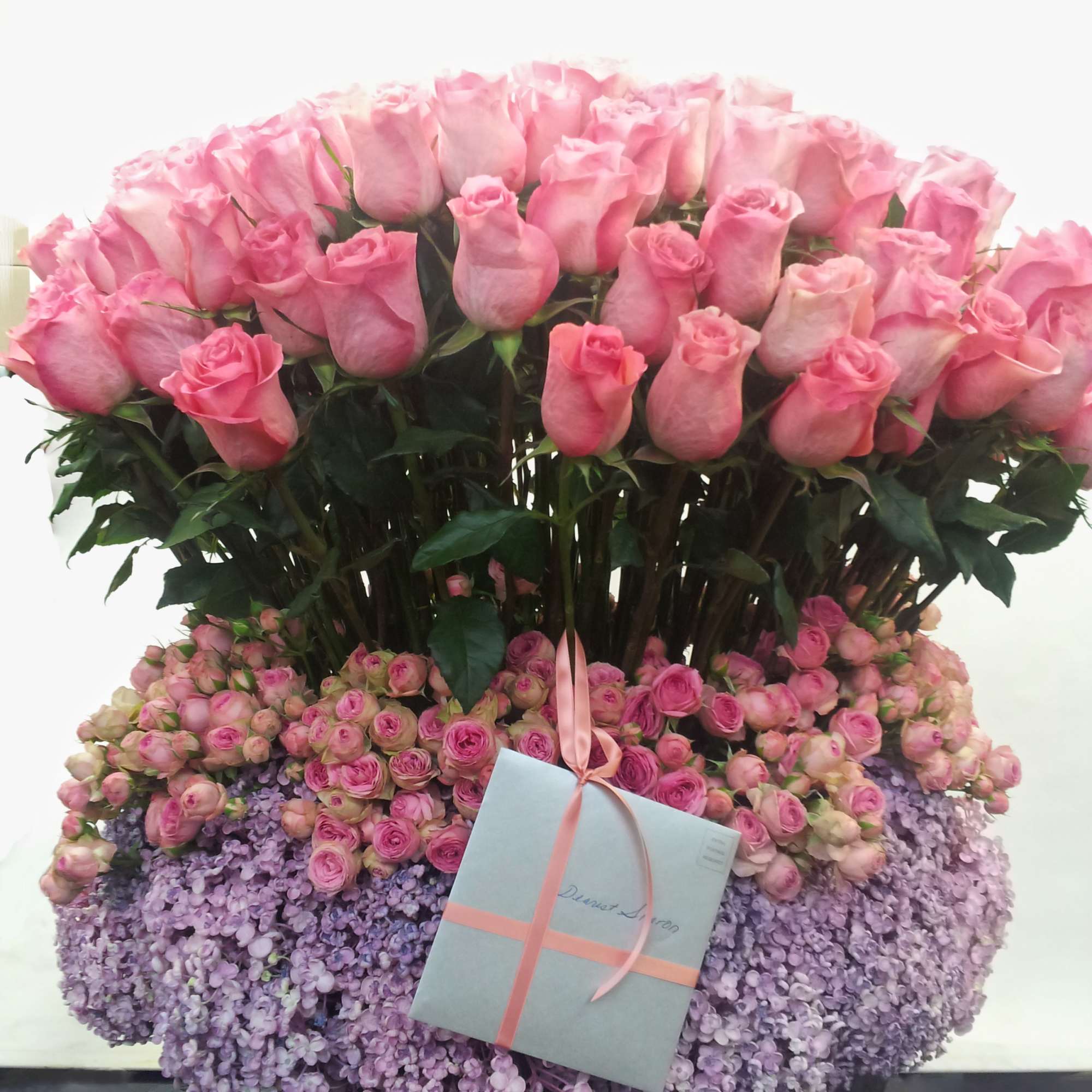Large pink rose arrangement with a gift box and ribbon