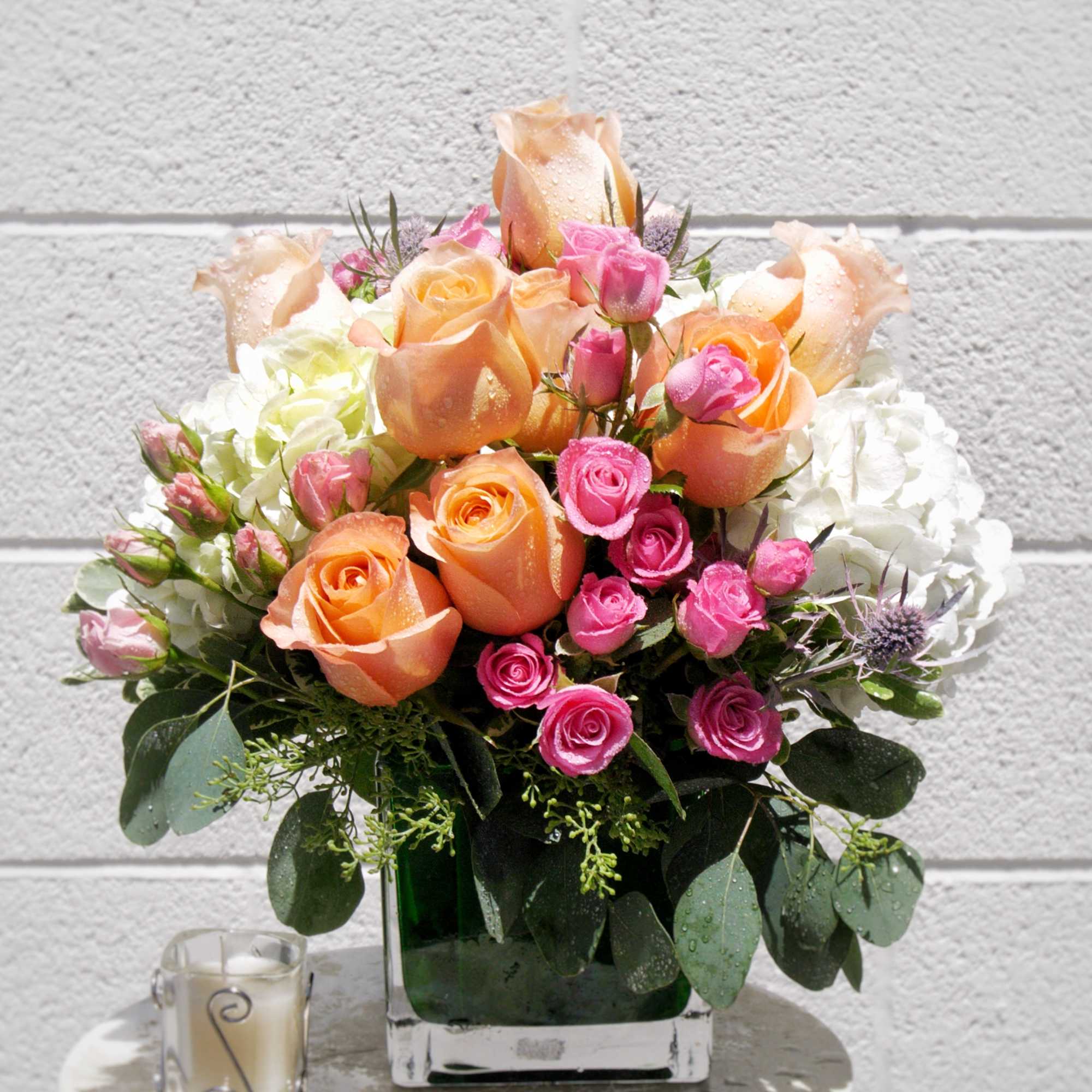 Bouquet of peach and pink roses in a square glass vase