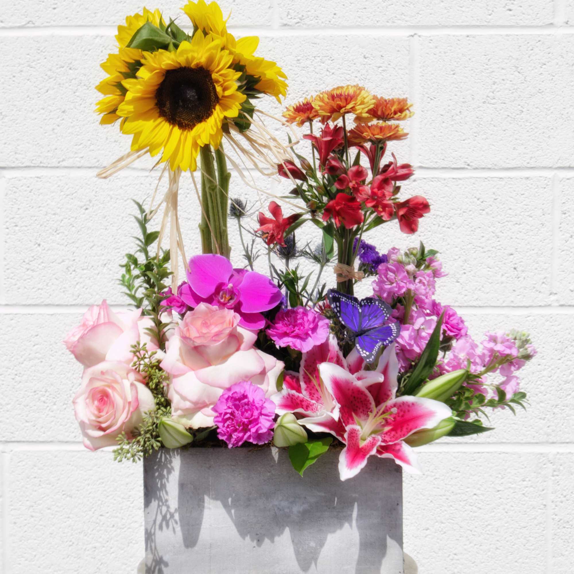 Mixed bouquet in a gray box with sunflowers, roses, lilies, and orchids