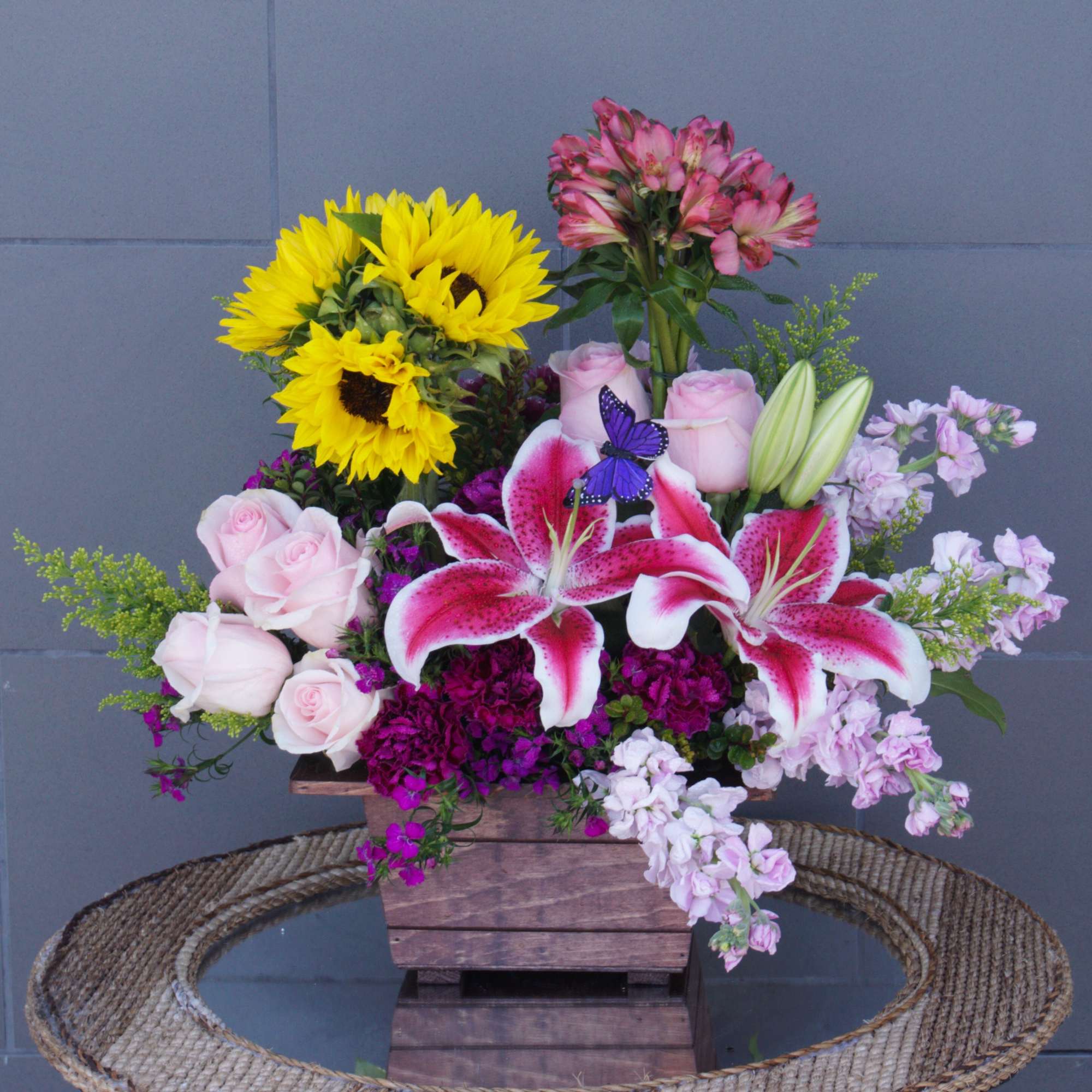 Mixed bouquet with sunflowers, pink roses, lilies, and alstroemeria in a wooden box