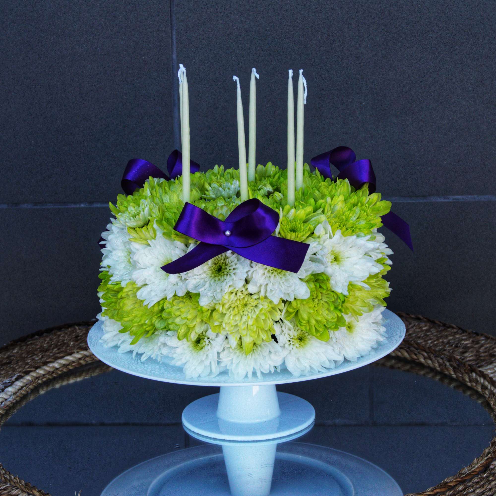 White and green chrysanthemum cake with purple ribbon and candles