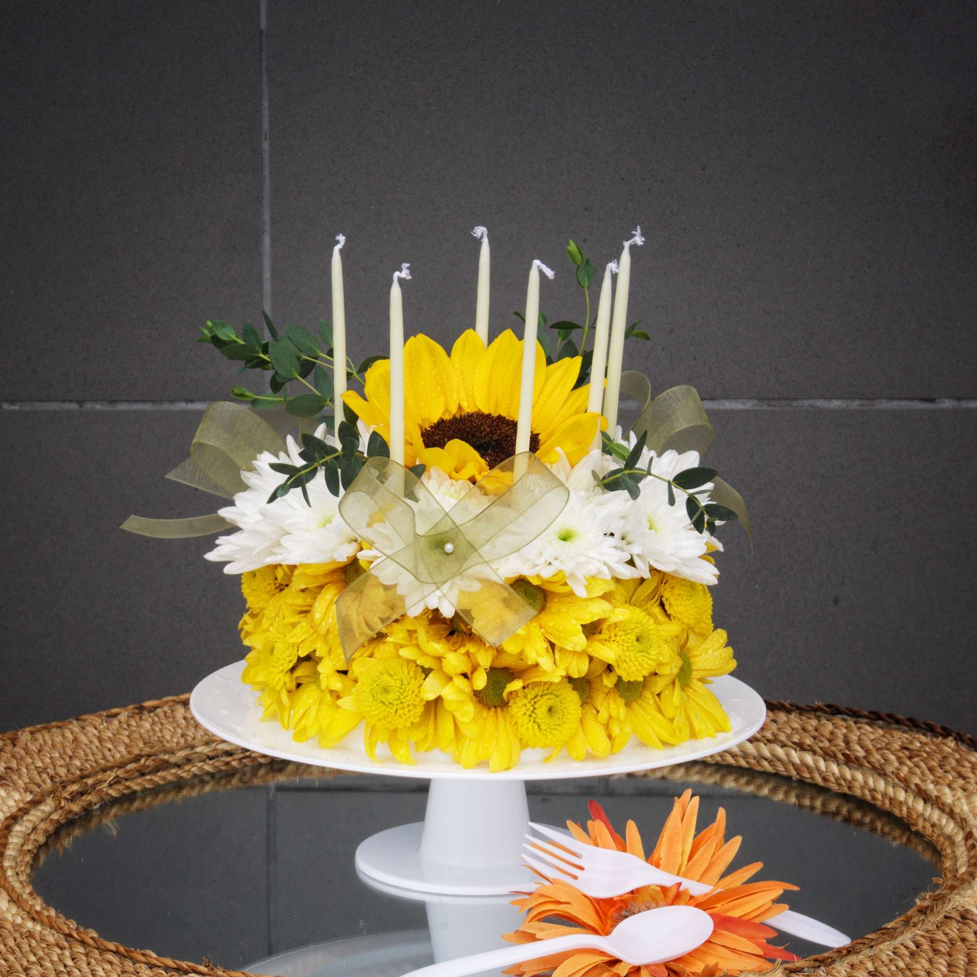 Yellow and white flower cake with candles on a white stand