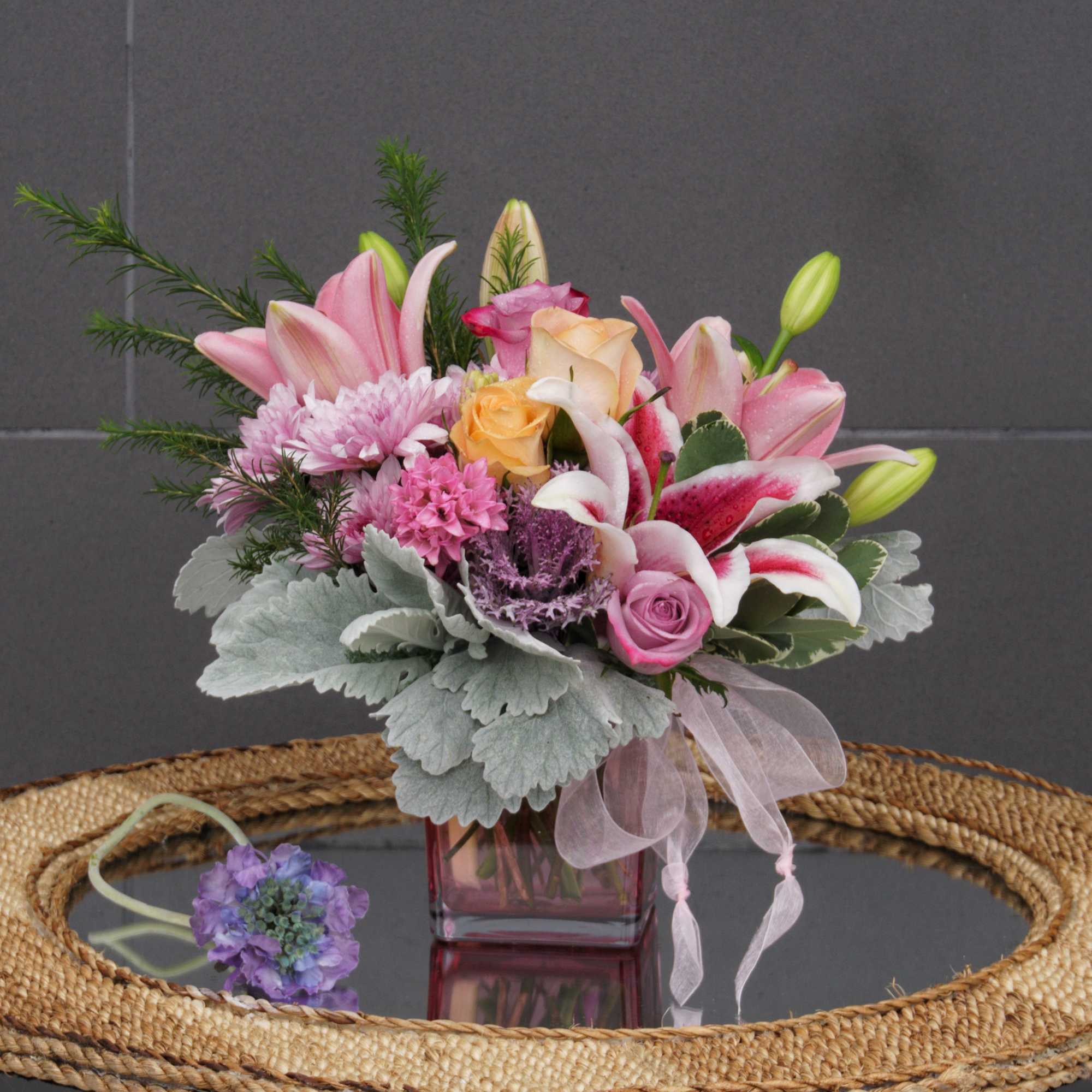 Pink and white mixed flower arrangement in a square glass vase
