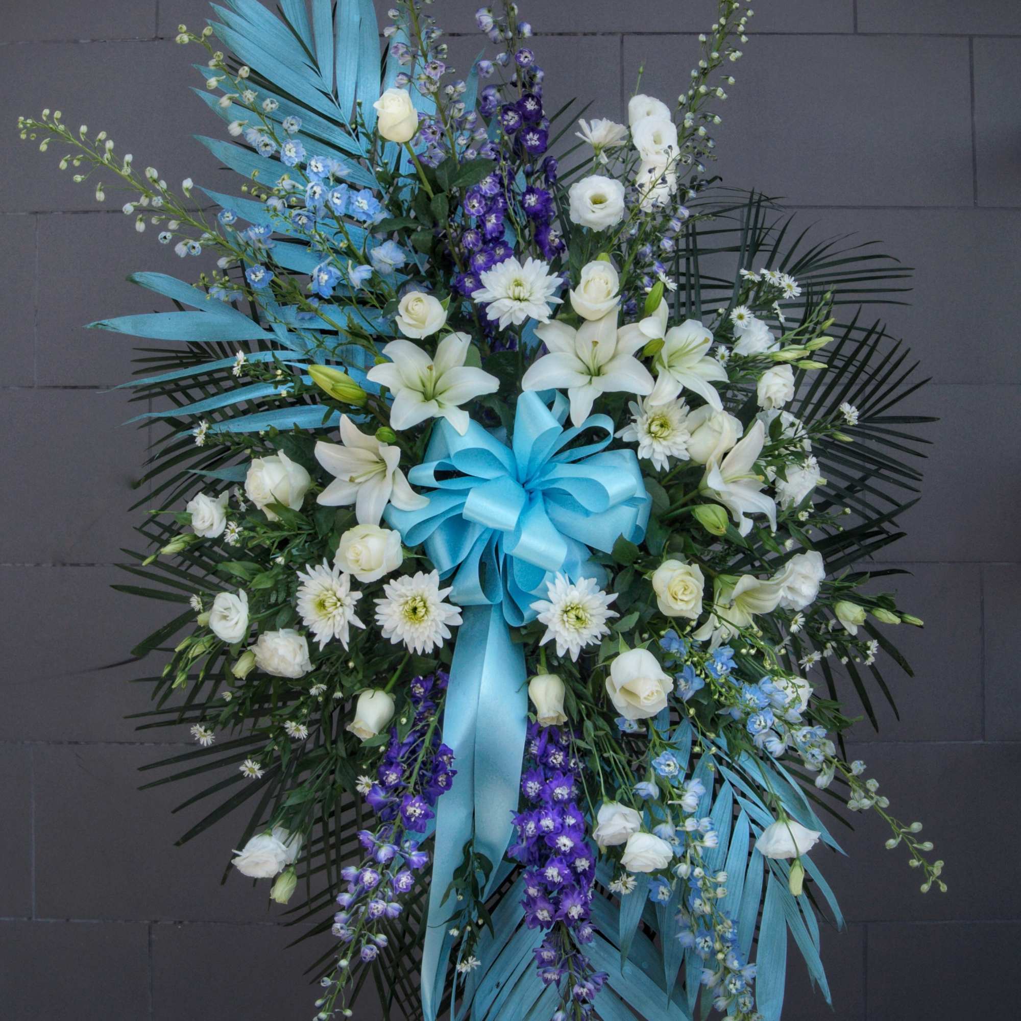 Tall white and blue floral standing spray with ribbon on an easel