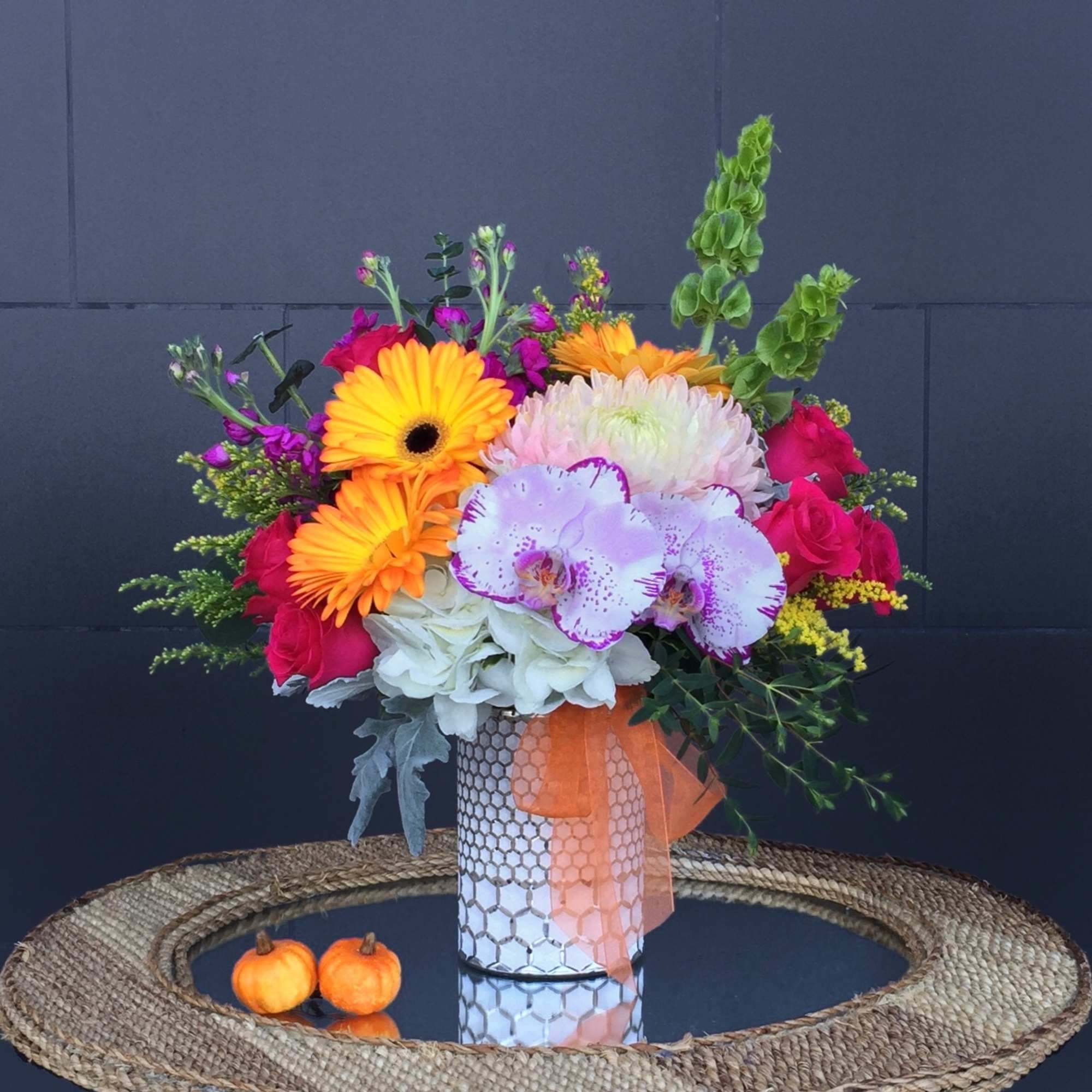 Bright mixed bouquet in a patterned vase with a ribbon
