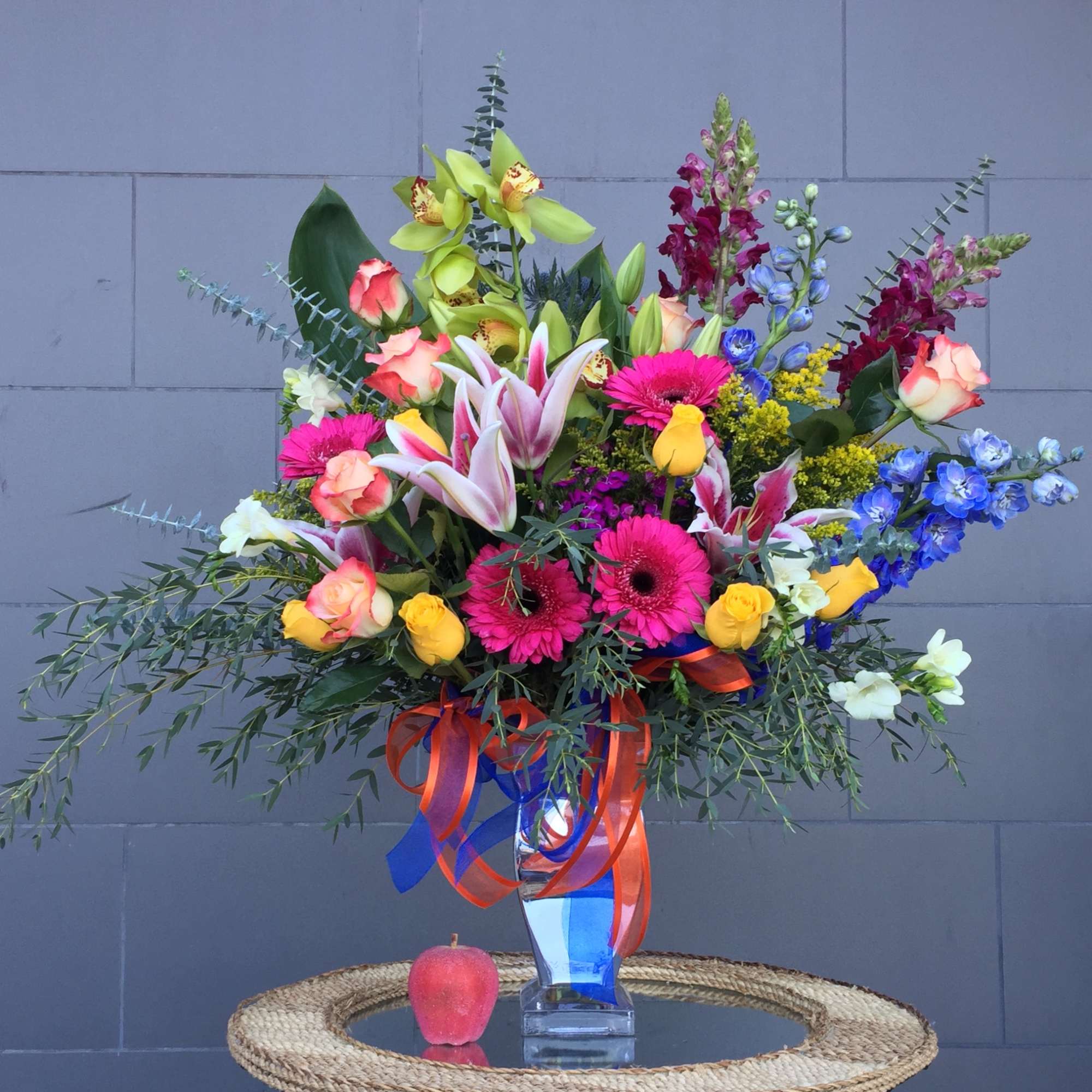 Colorful mixed bouquet in a clear vase with ribbon streamers