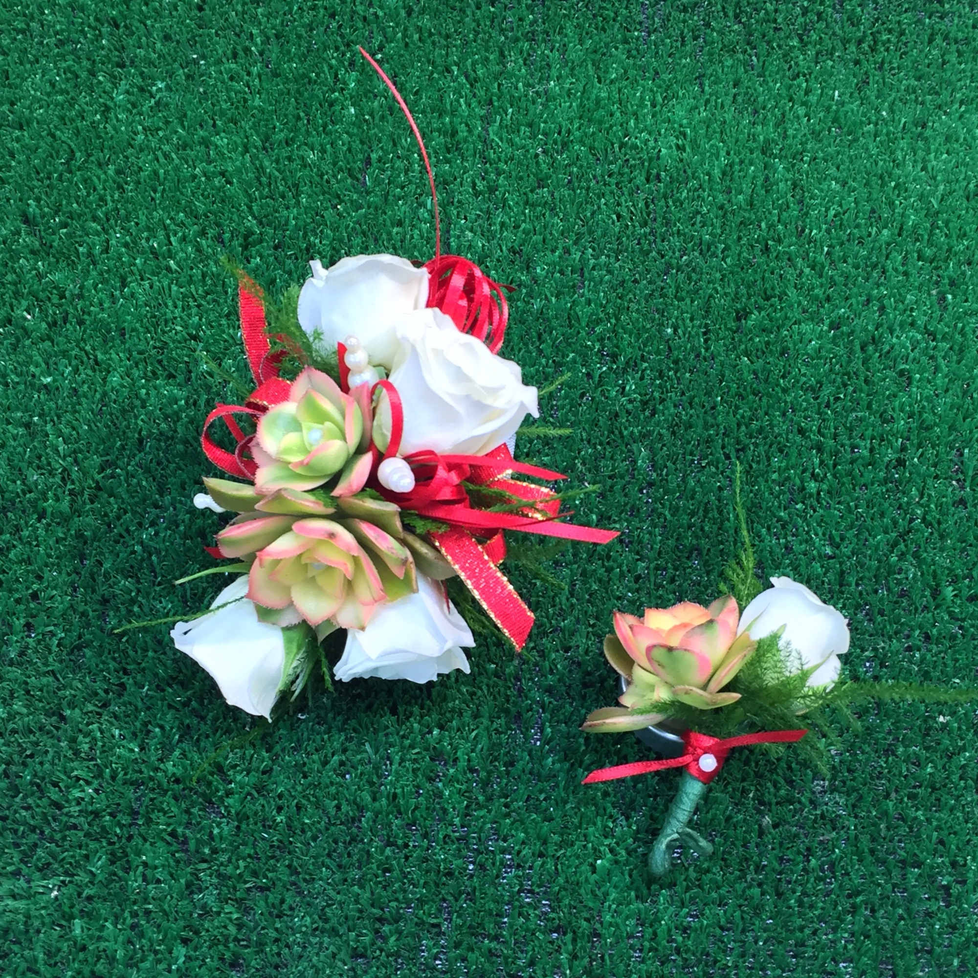 Two small floral pieces with white roses and succulents on grass