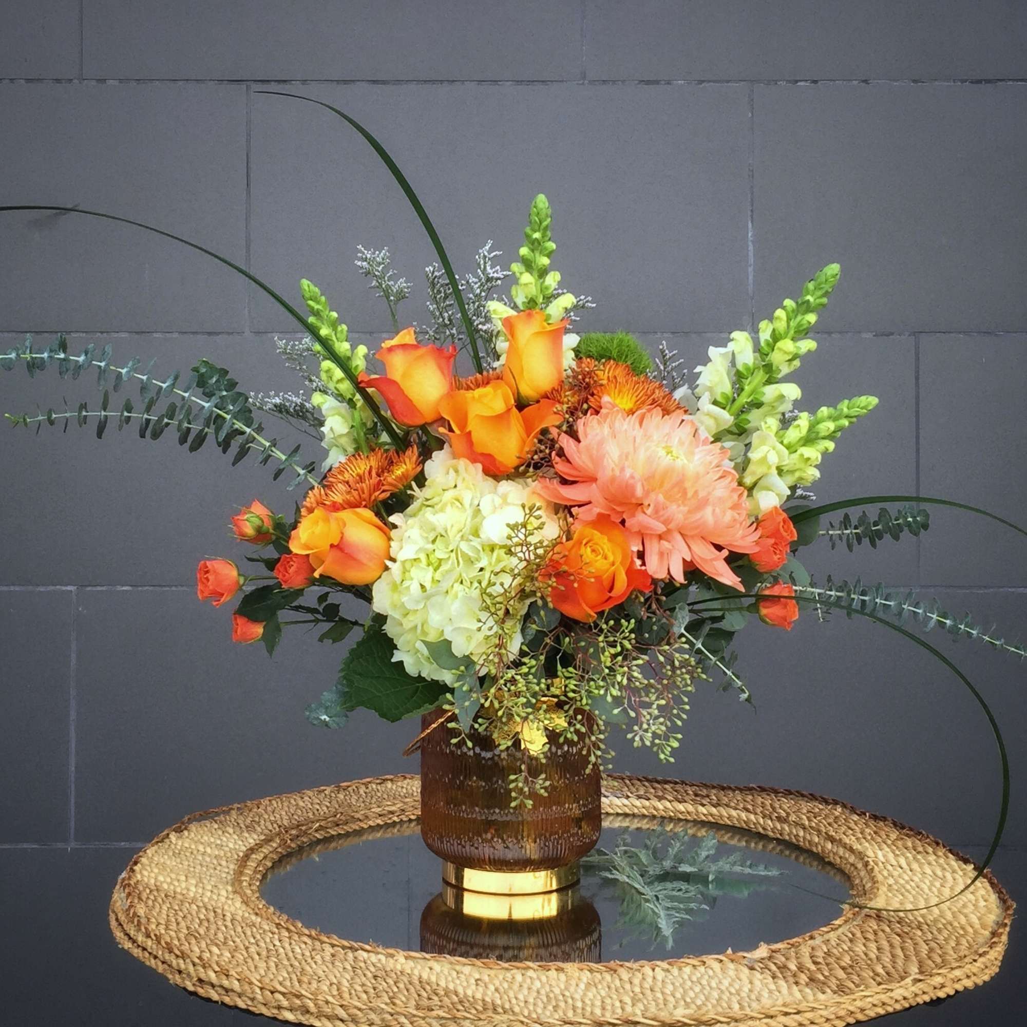 Orange and peach floral arrangement in a brown vase