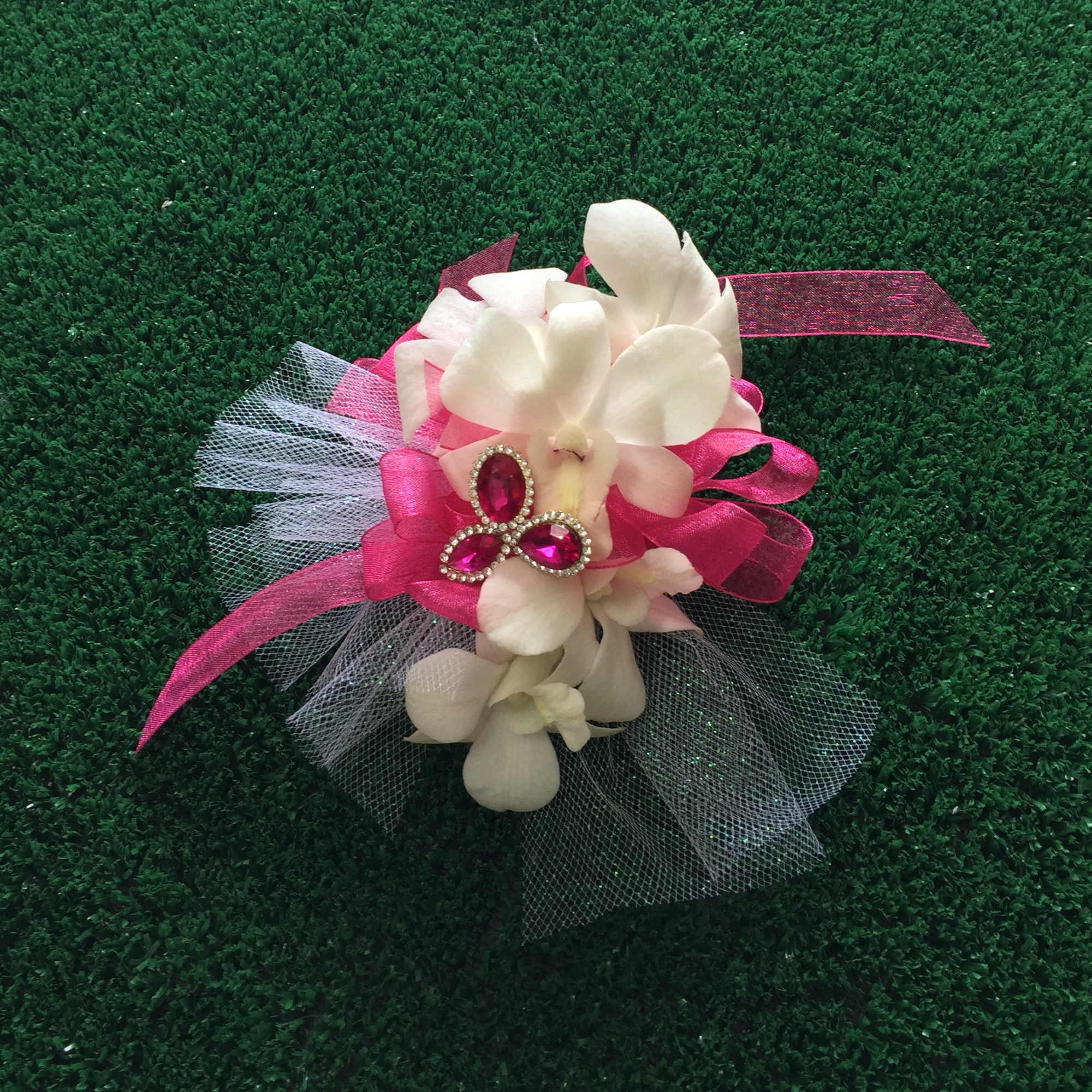 White orchid corsage with pink ribbon and jeweled accent