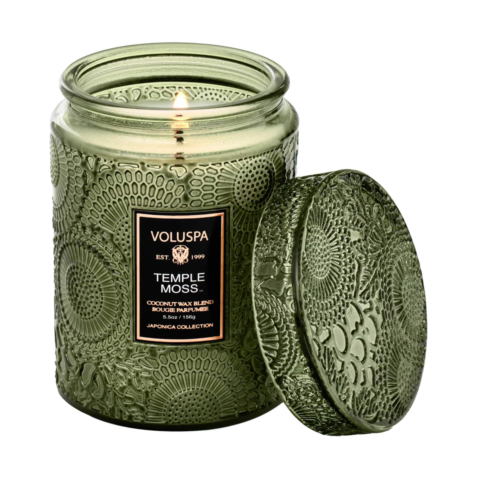 Green glass candle jar with a lit wick and matching lid