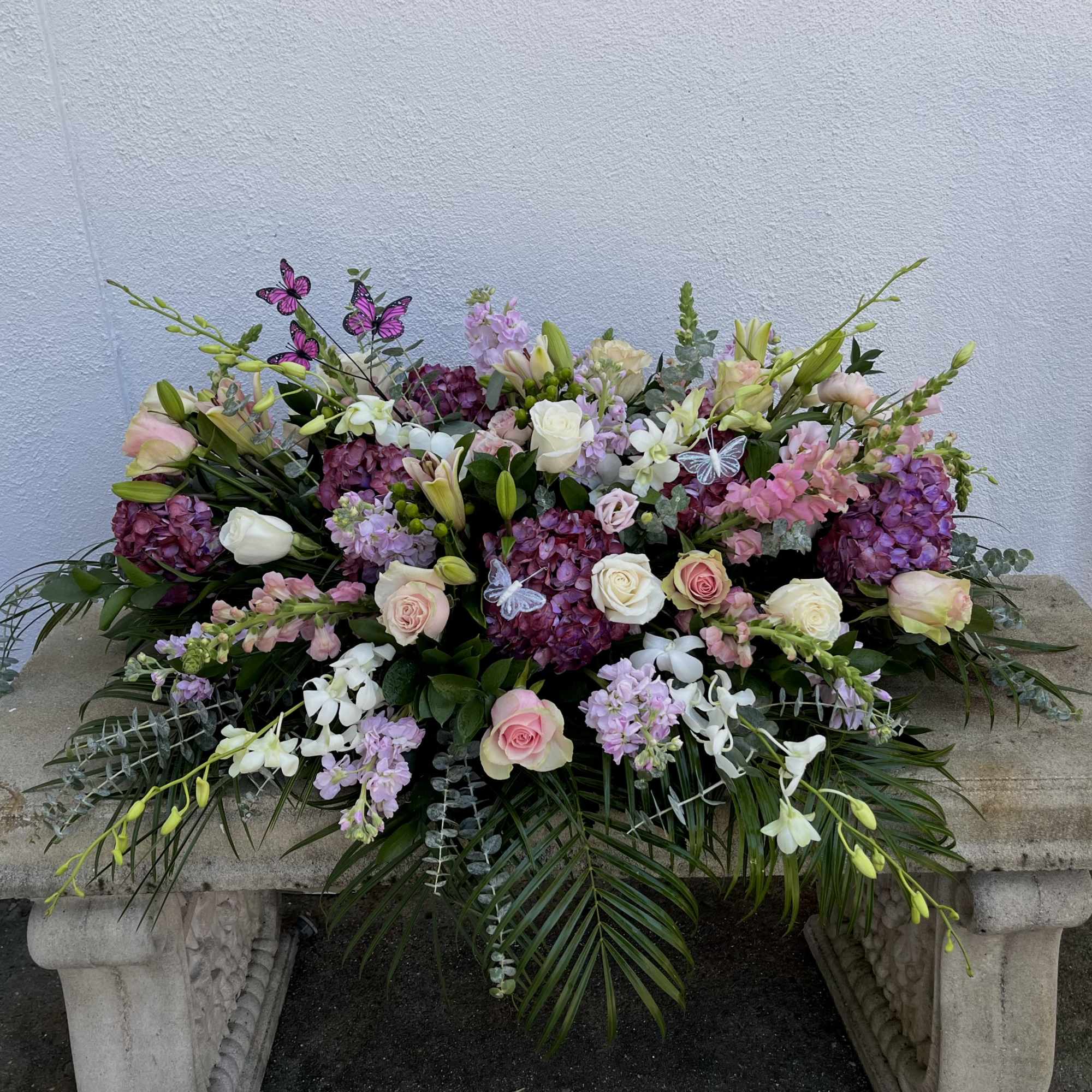 Large floral arrangement with pink and white roses, lilies, and purple blooms