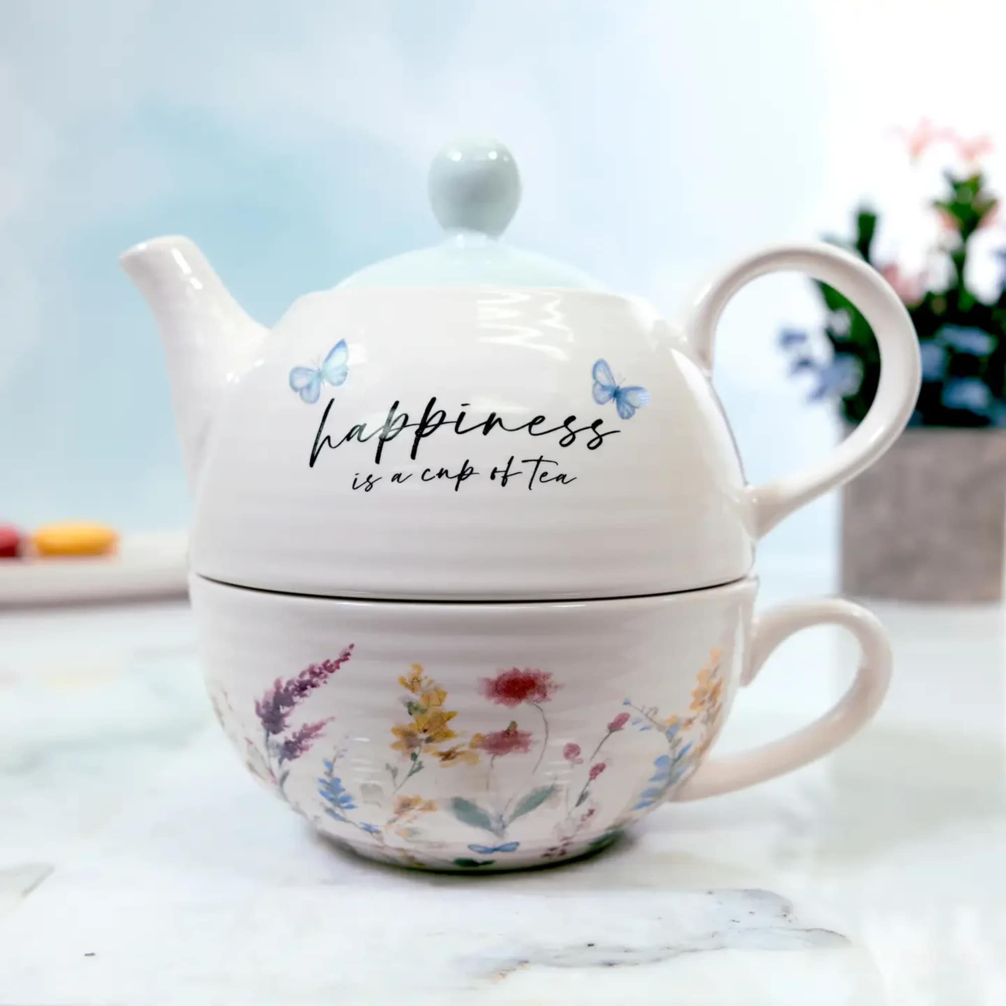 Stacked ceramic teapot and teacup with floral and butterfly designs