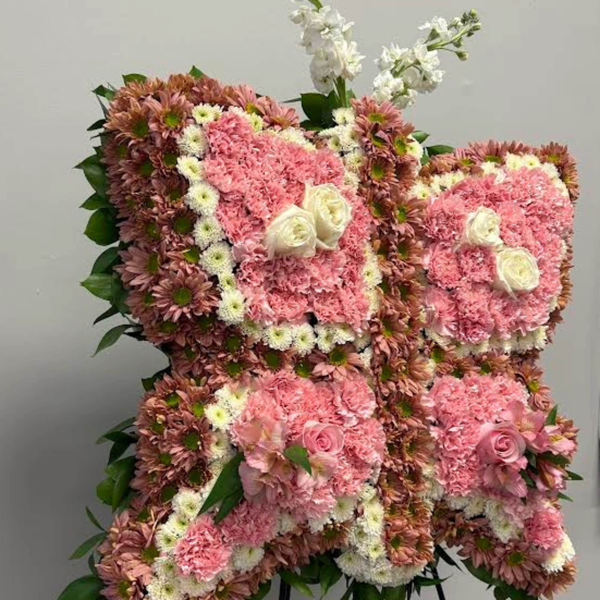 Pink floral standing arrangement on an easel with white accents