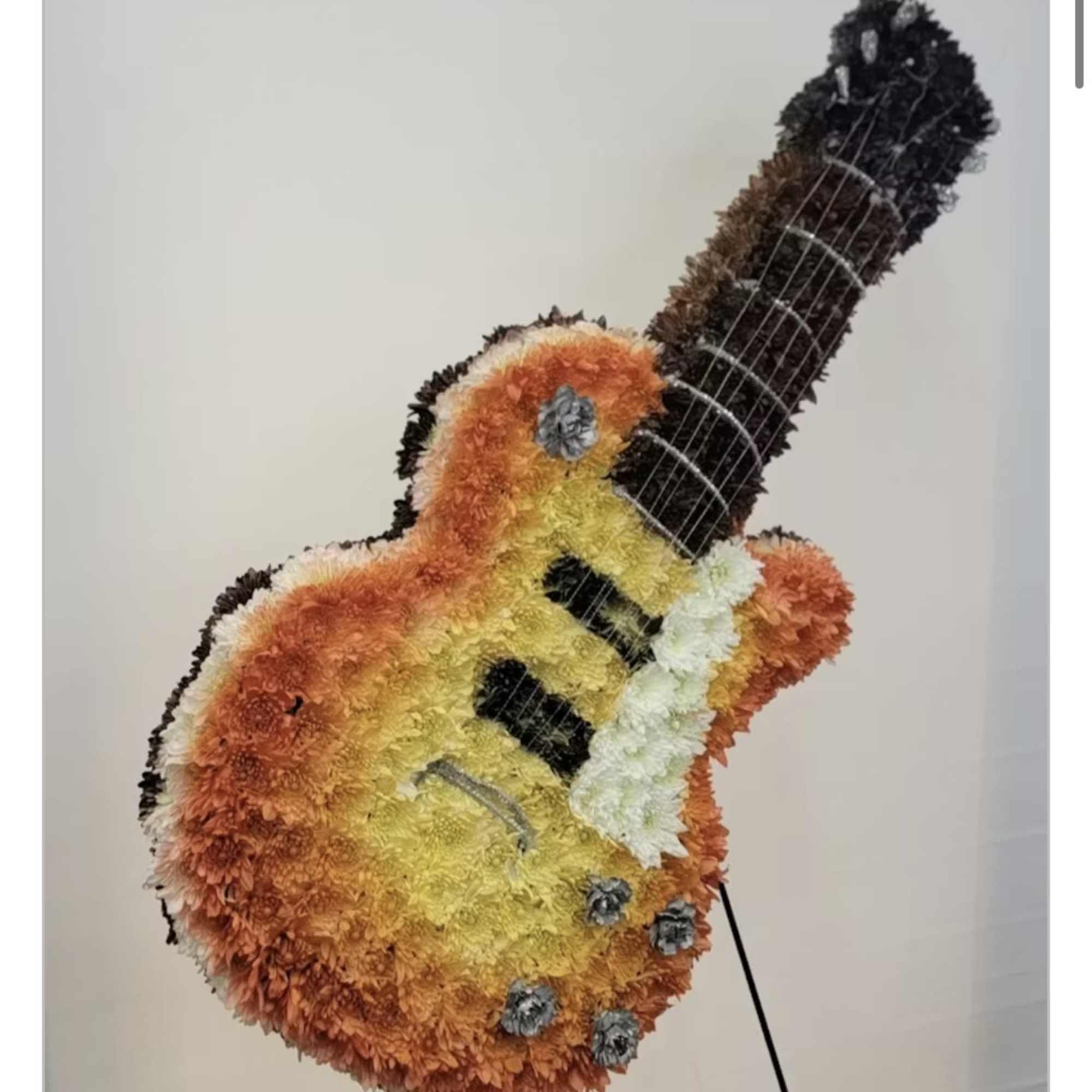 Flower-covered guitar display in orange, yellow, white, and black.