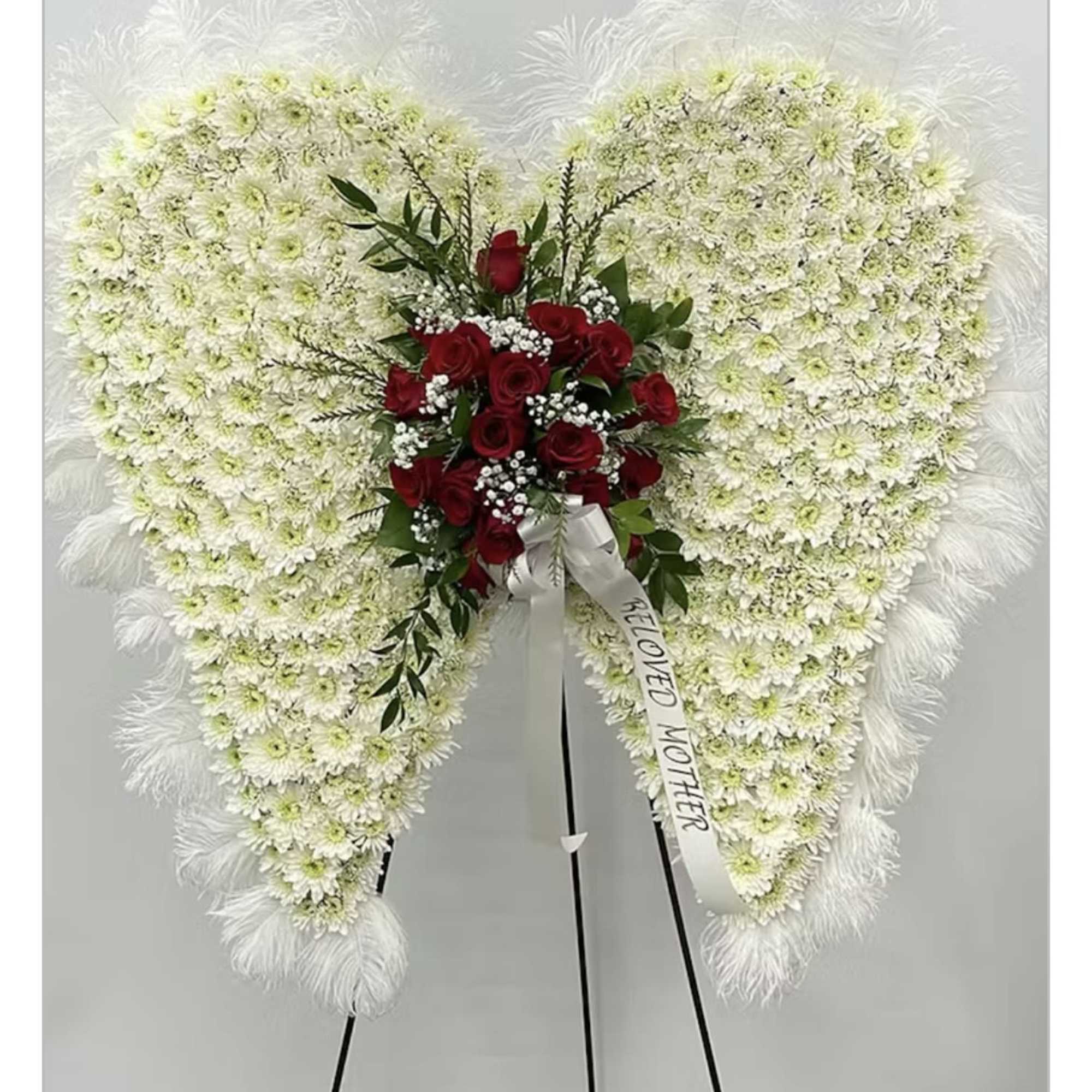 Heart-shaped white floral standing spray with red roses and a ribbon