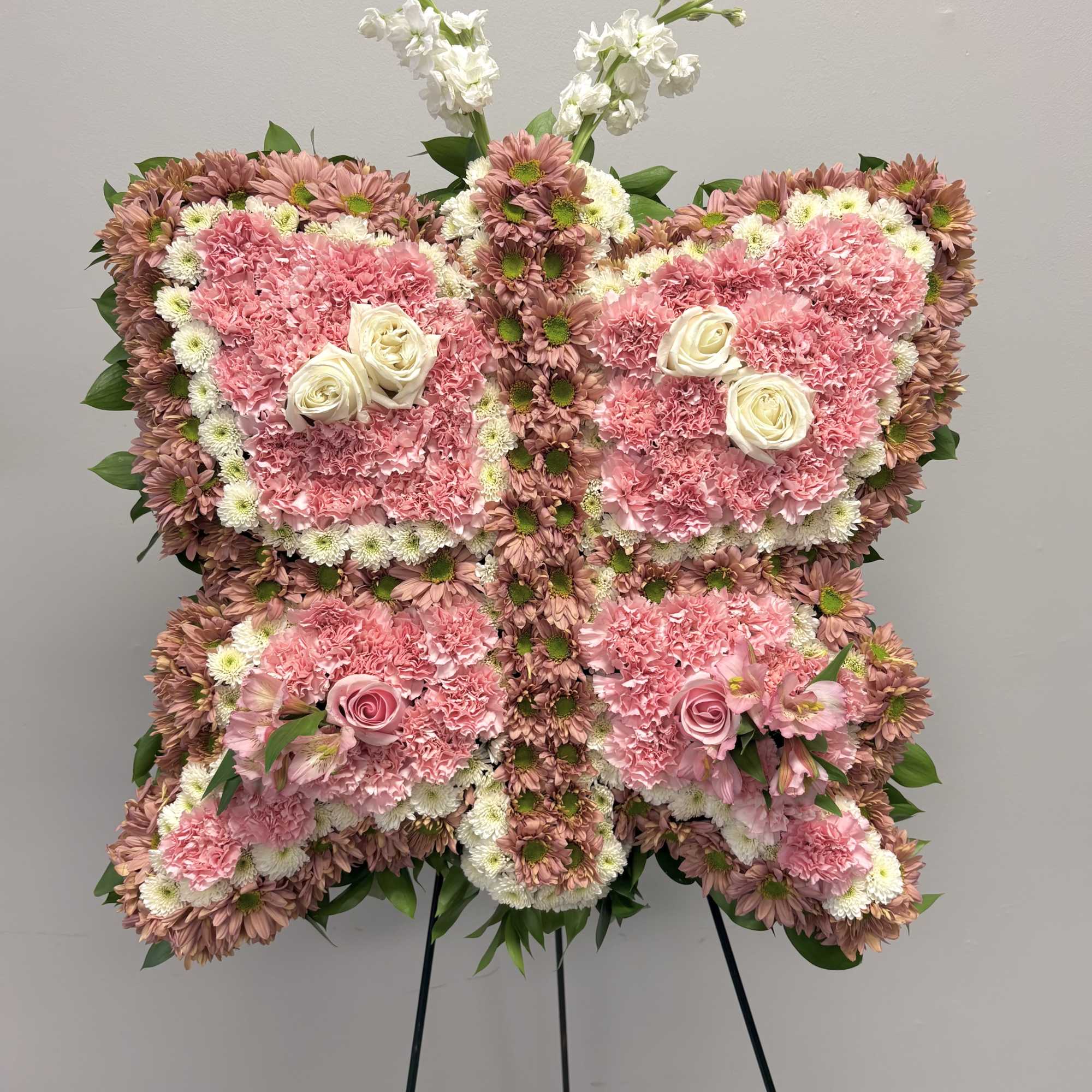 Butterfly-shaped floral standing spray in pink and white on an easel
