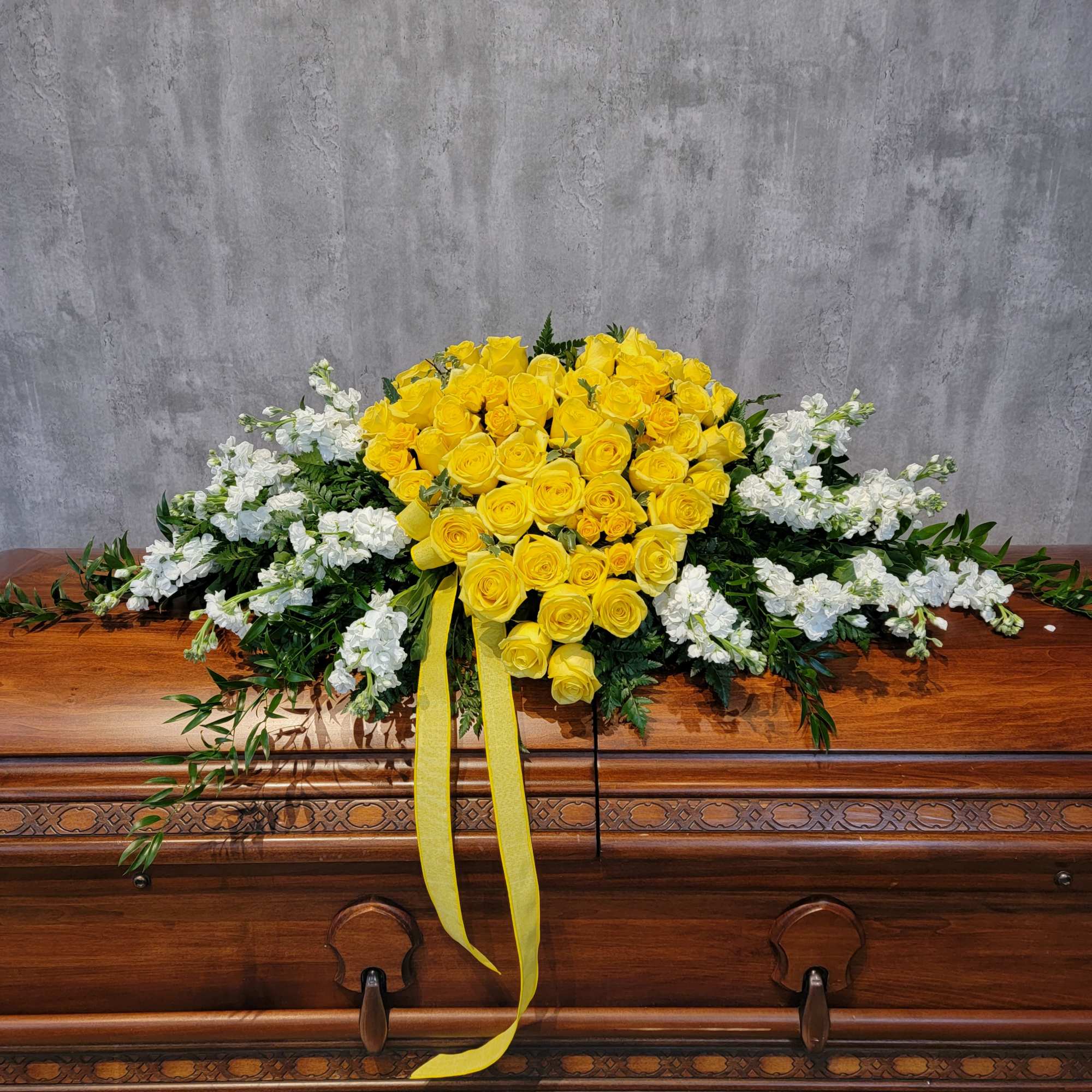 Yellow rose casket spray with white flowers and ribbon