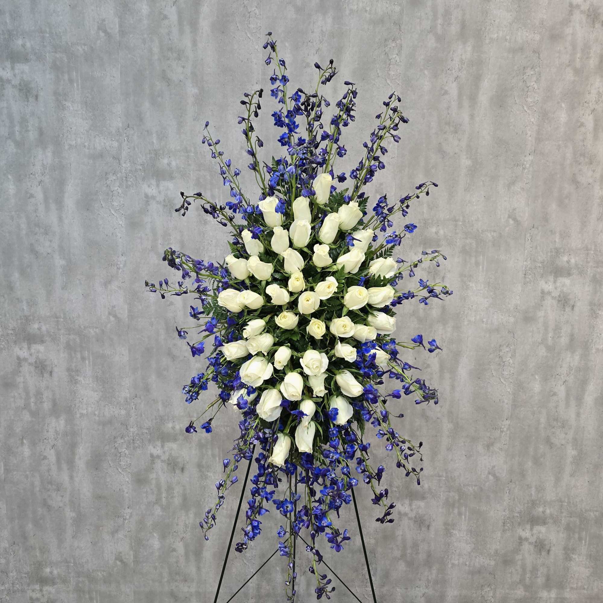 Standing floral spray of white roses and blue delphinium on an easel