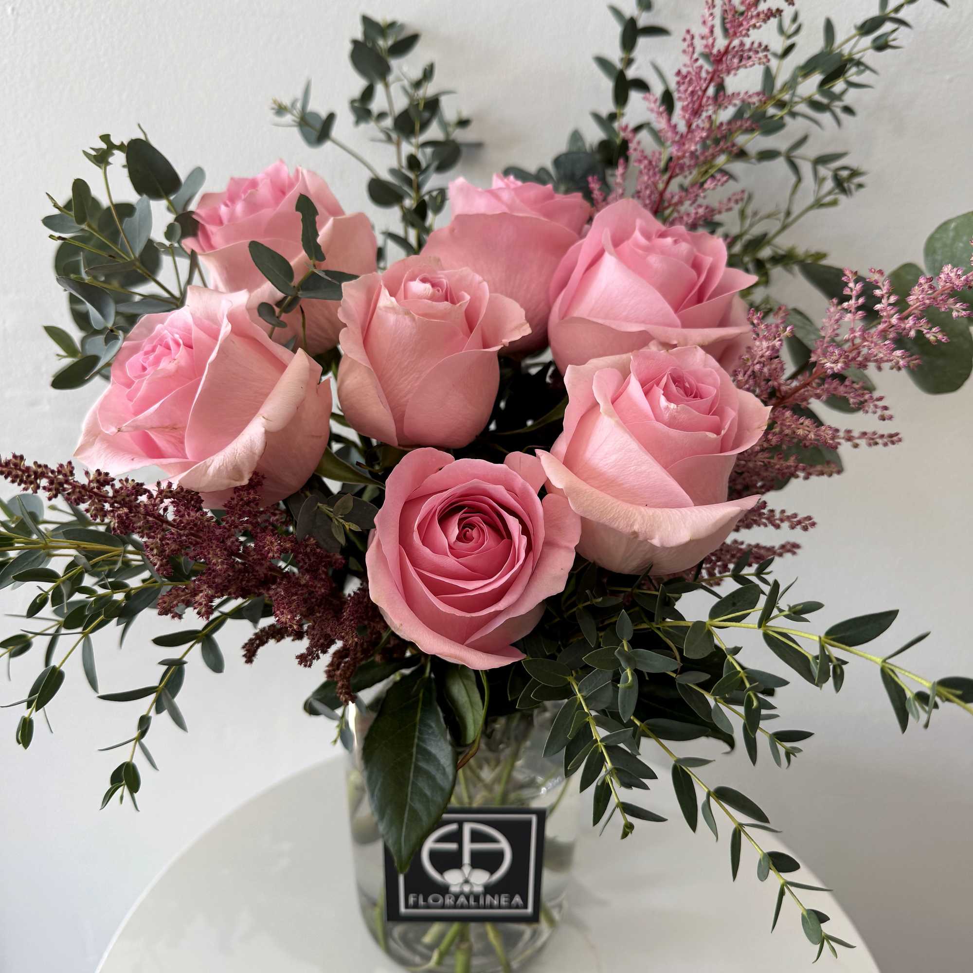 Pink roses in a clear glass vase with airy filler flowers