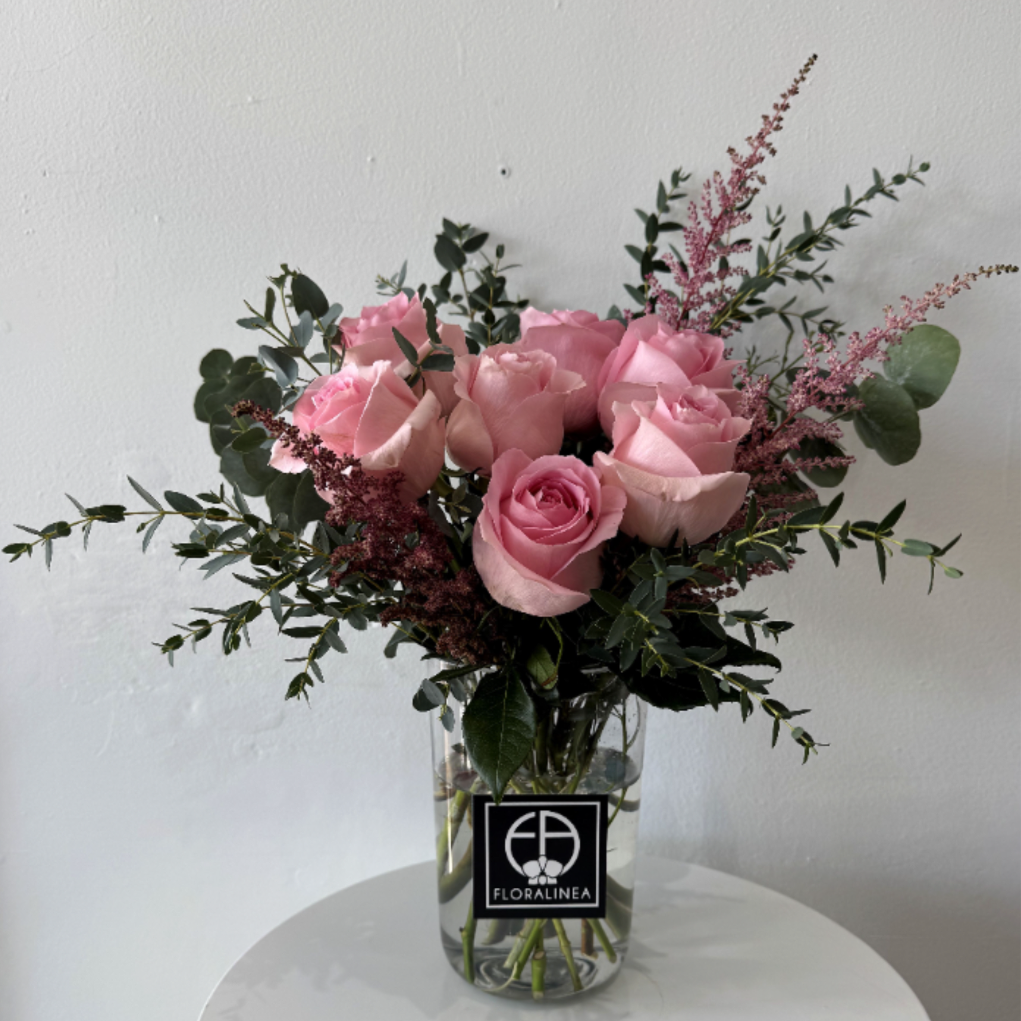 Pink roses in a clear glass vase with airy greenery