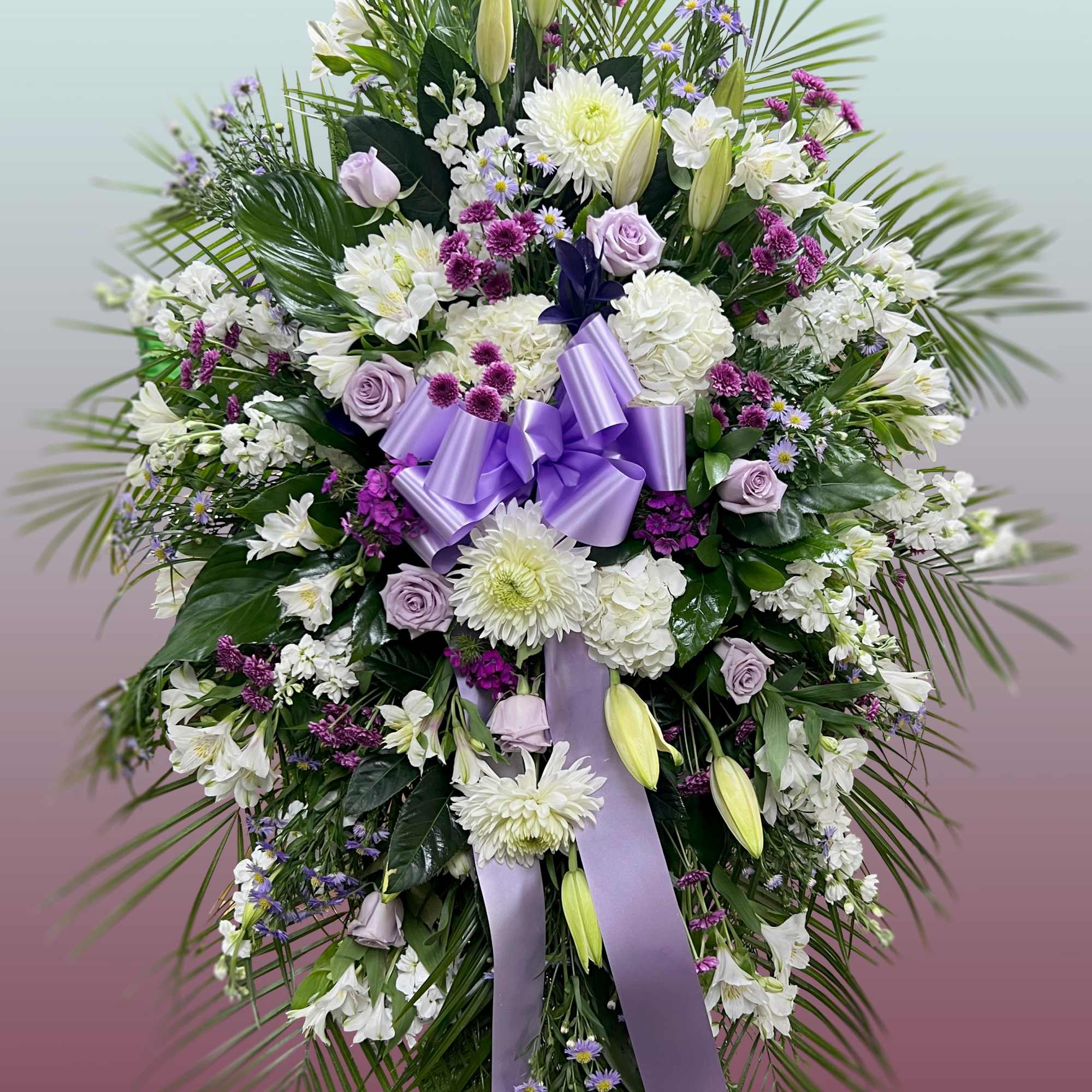 This easel spray is composed of lavender roses, mums, oriental lilies, dianthus