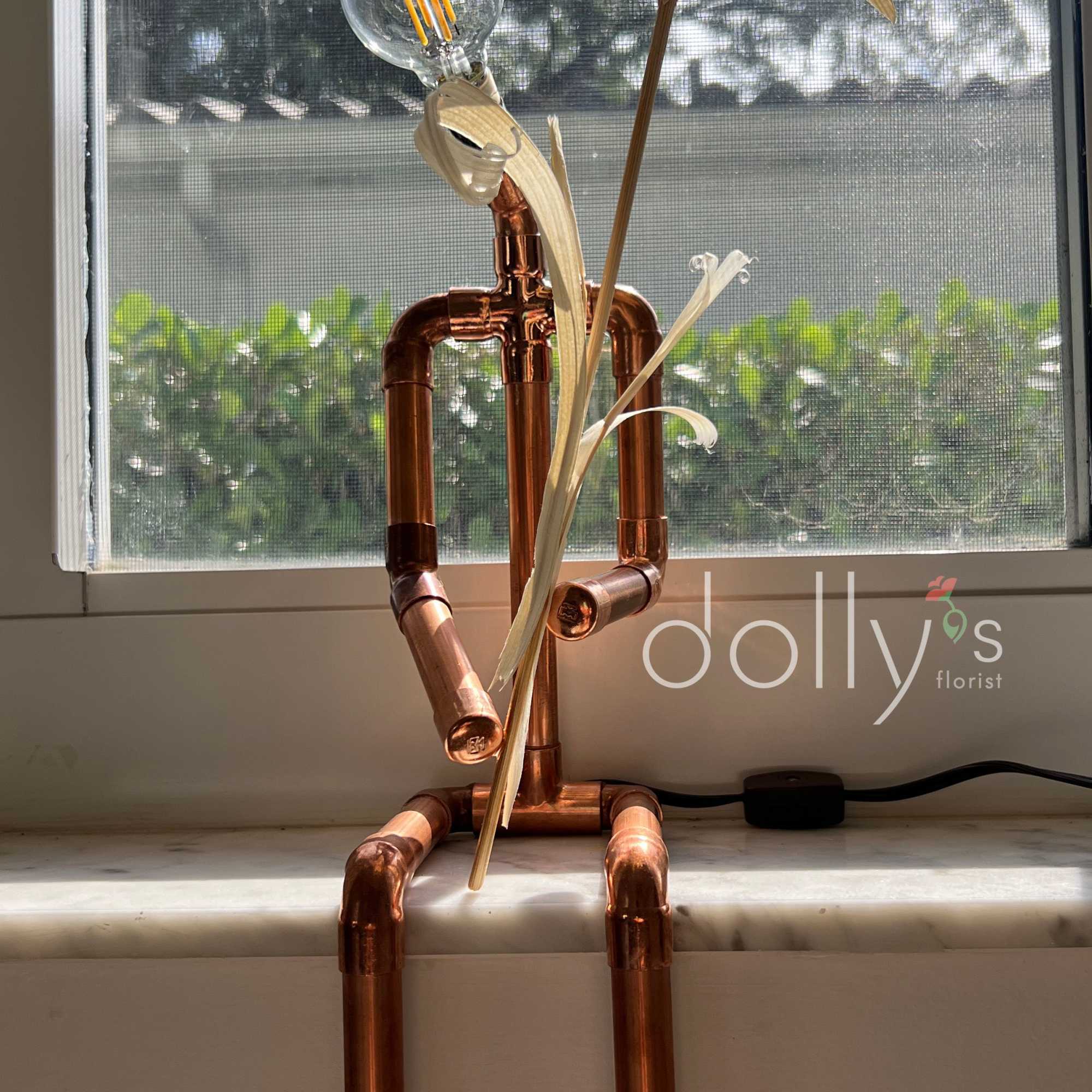 Copper pipe figure with a light bulb head and palm-like leaves