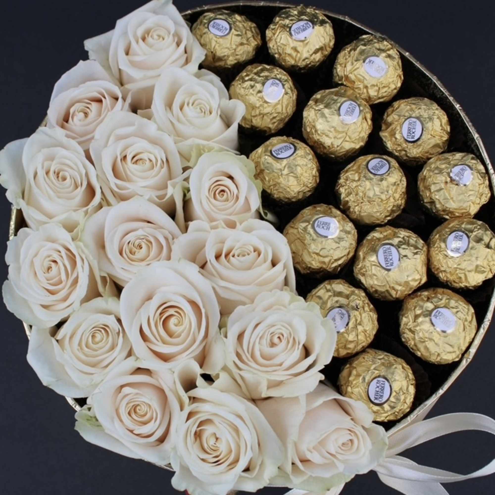 White roses arranged with gold-wrapped chocolates in a round box