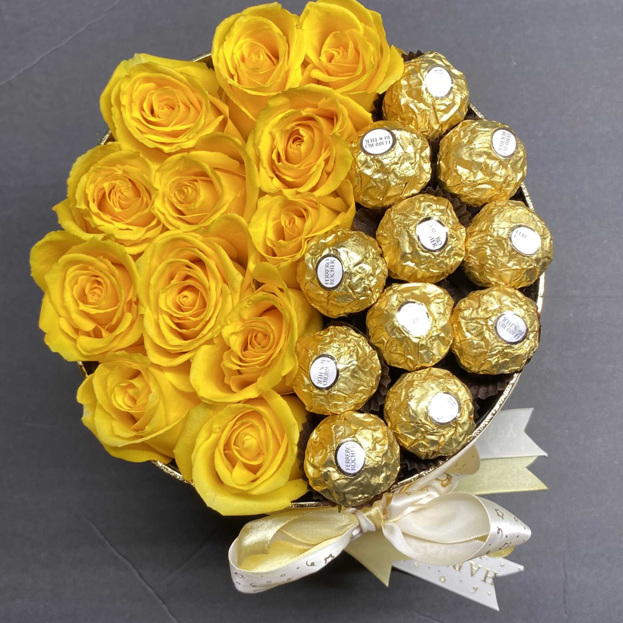 Yellow roses arranged with gold-wrapped chocolates in a round bouquet