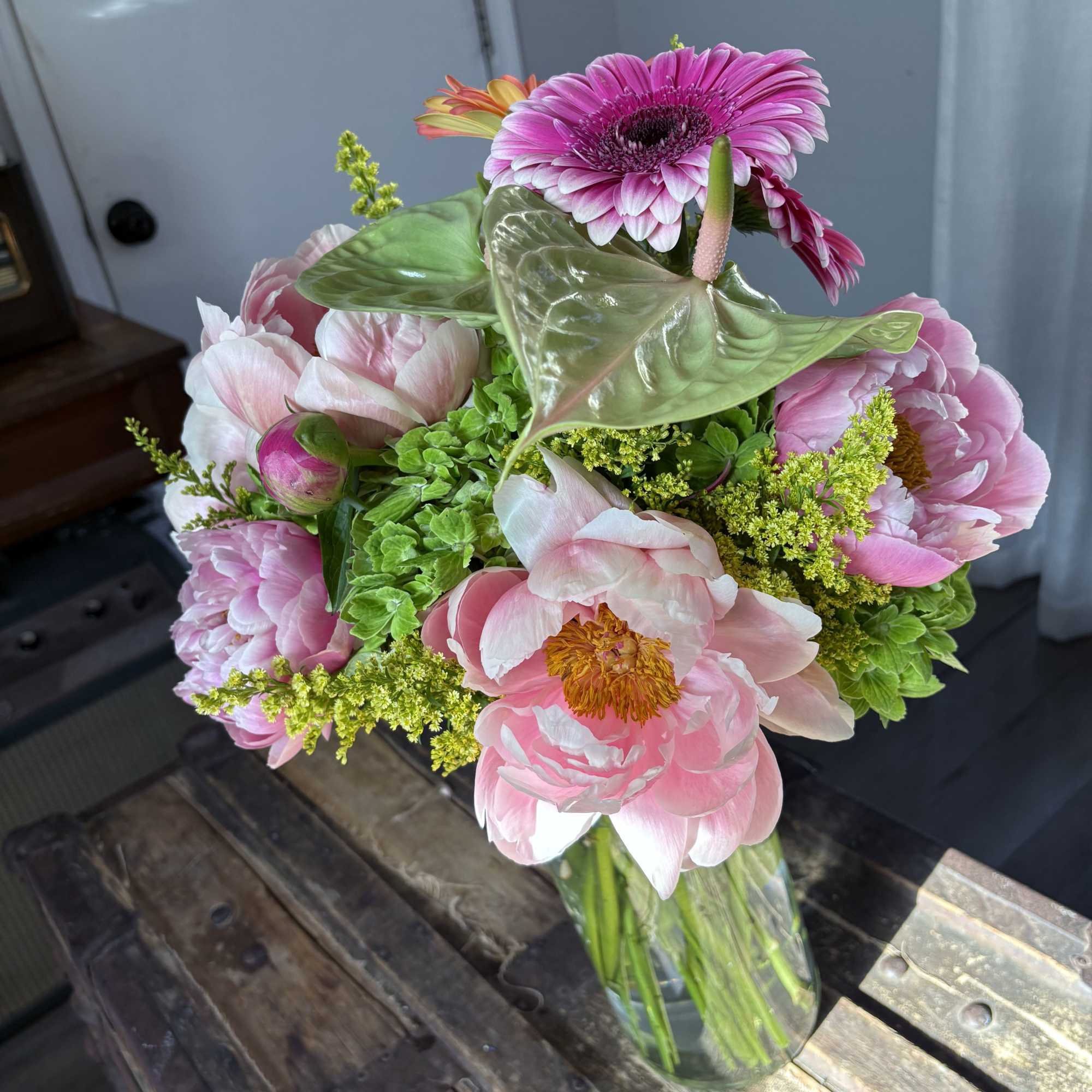 Pink peonies and a magenta gerbera daisy in a glass vase
