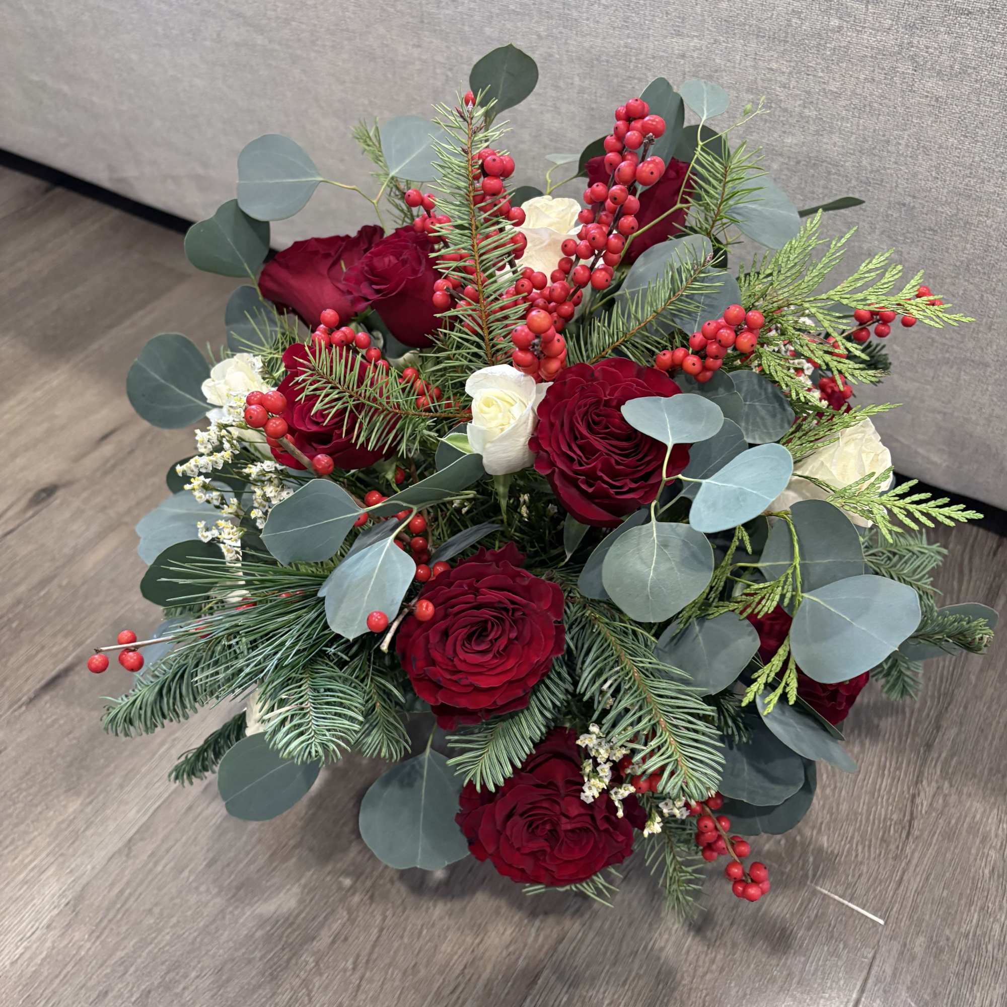 Bouquet of red roses with white blooms, berries, and evergreen foliage
