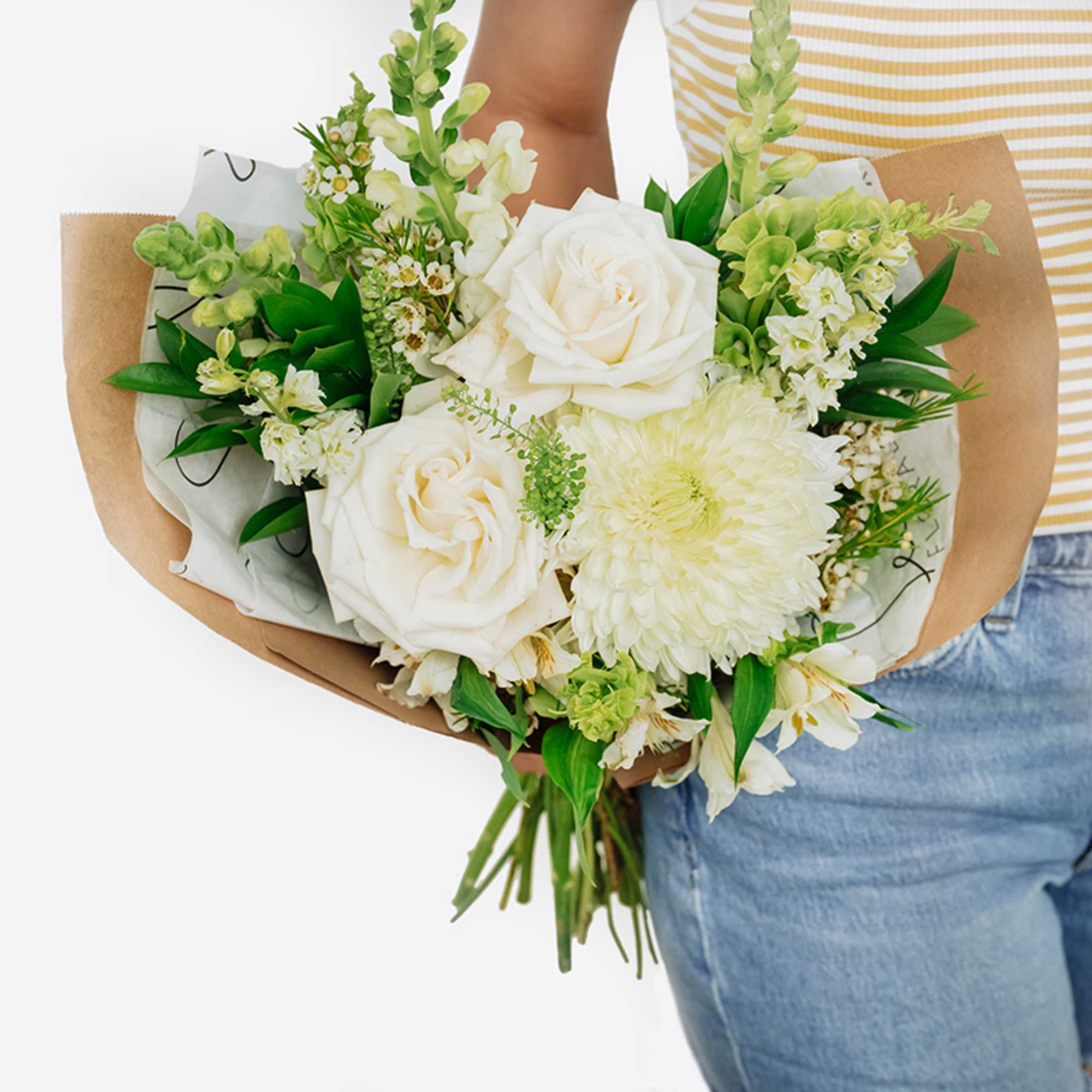 Bouquet of white roses and pale blooms wrapped in brown paper