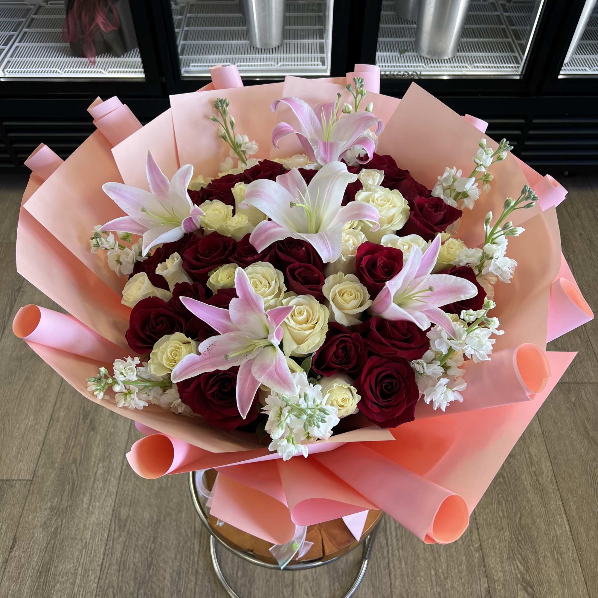 A lush cluster of deep red and ivory roses framed by pink-and
