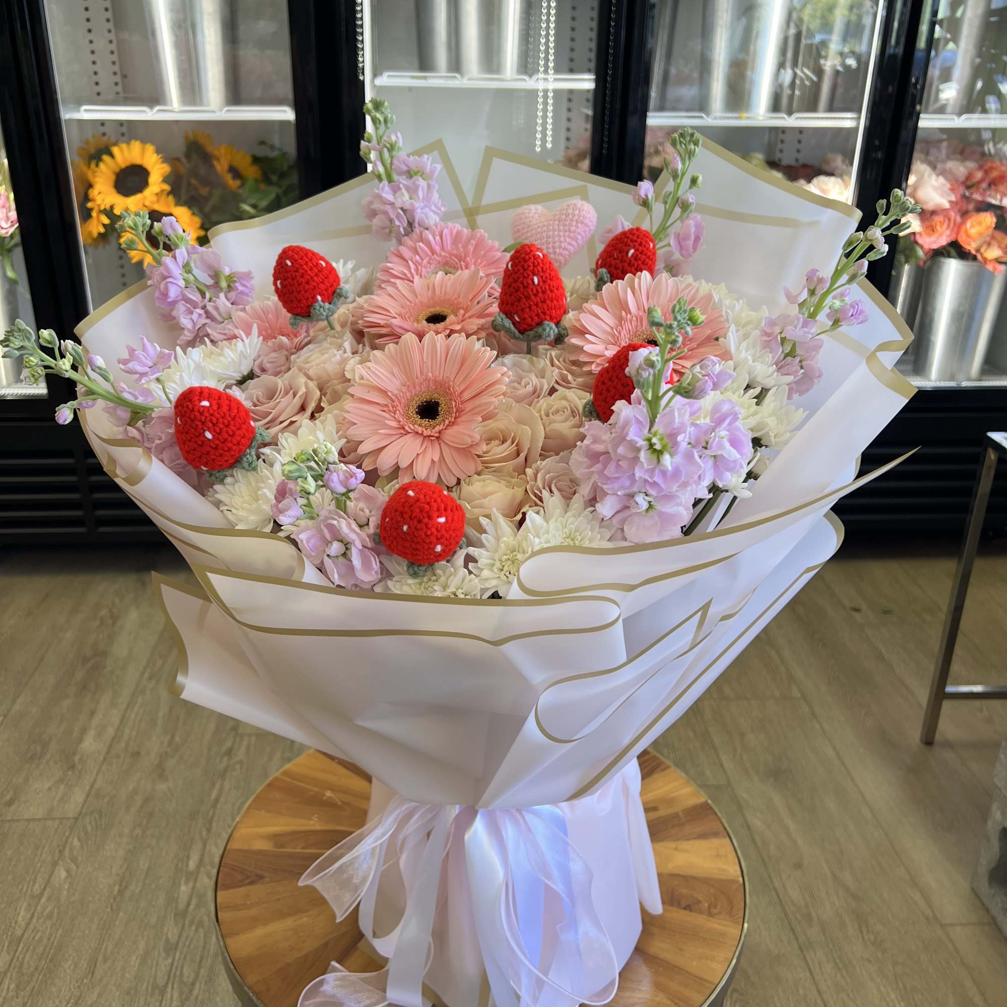 Pink and white bouquet with red strawberry decorations wrapped in white paper