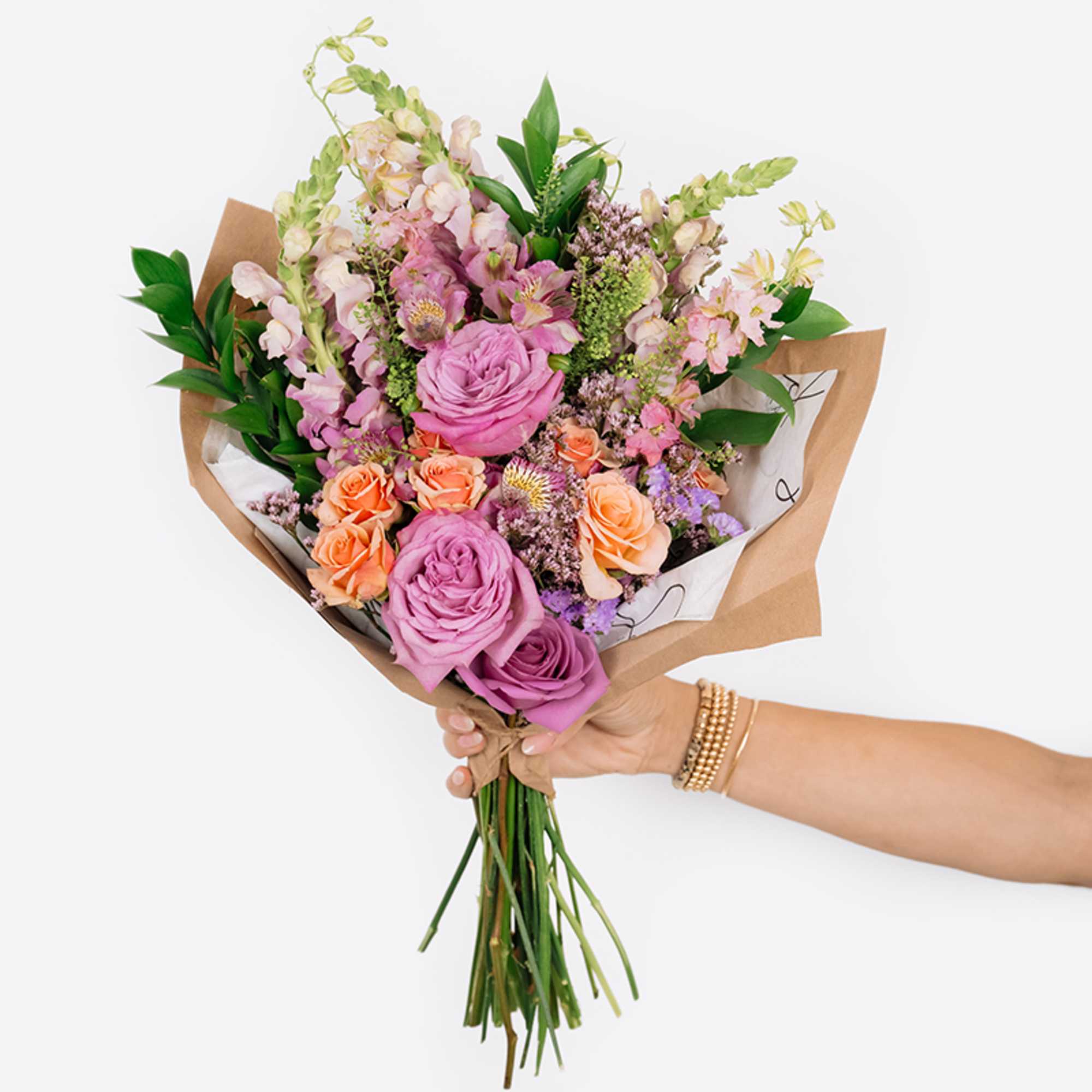 Handheld bouquet of pink and peach roses with mixed blooms