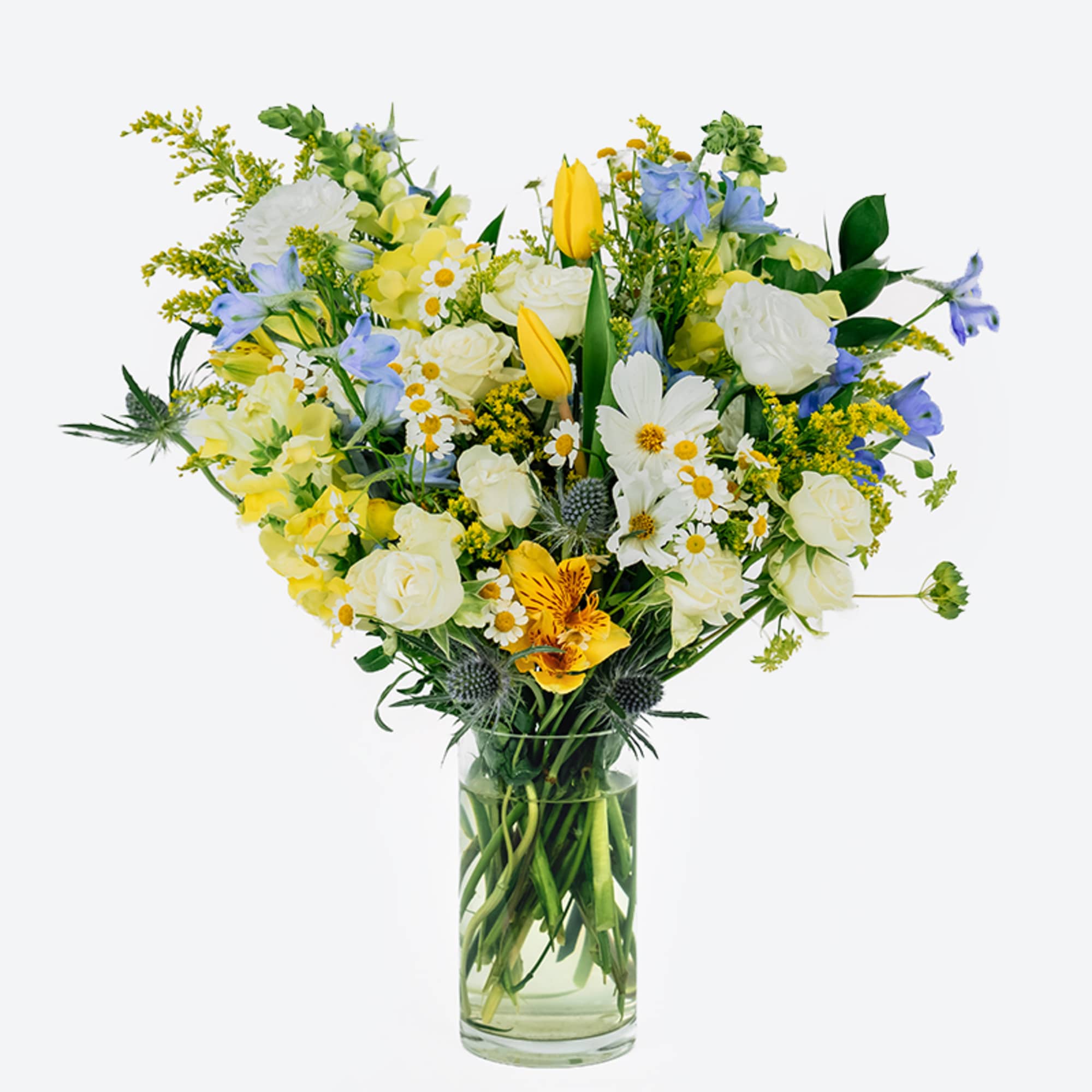 Mixed bouquet of white, yellow, and blue flowers in a clear glass vase