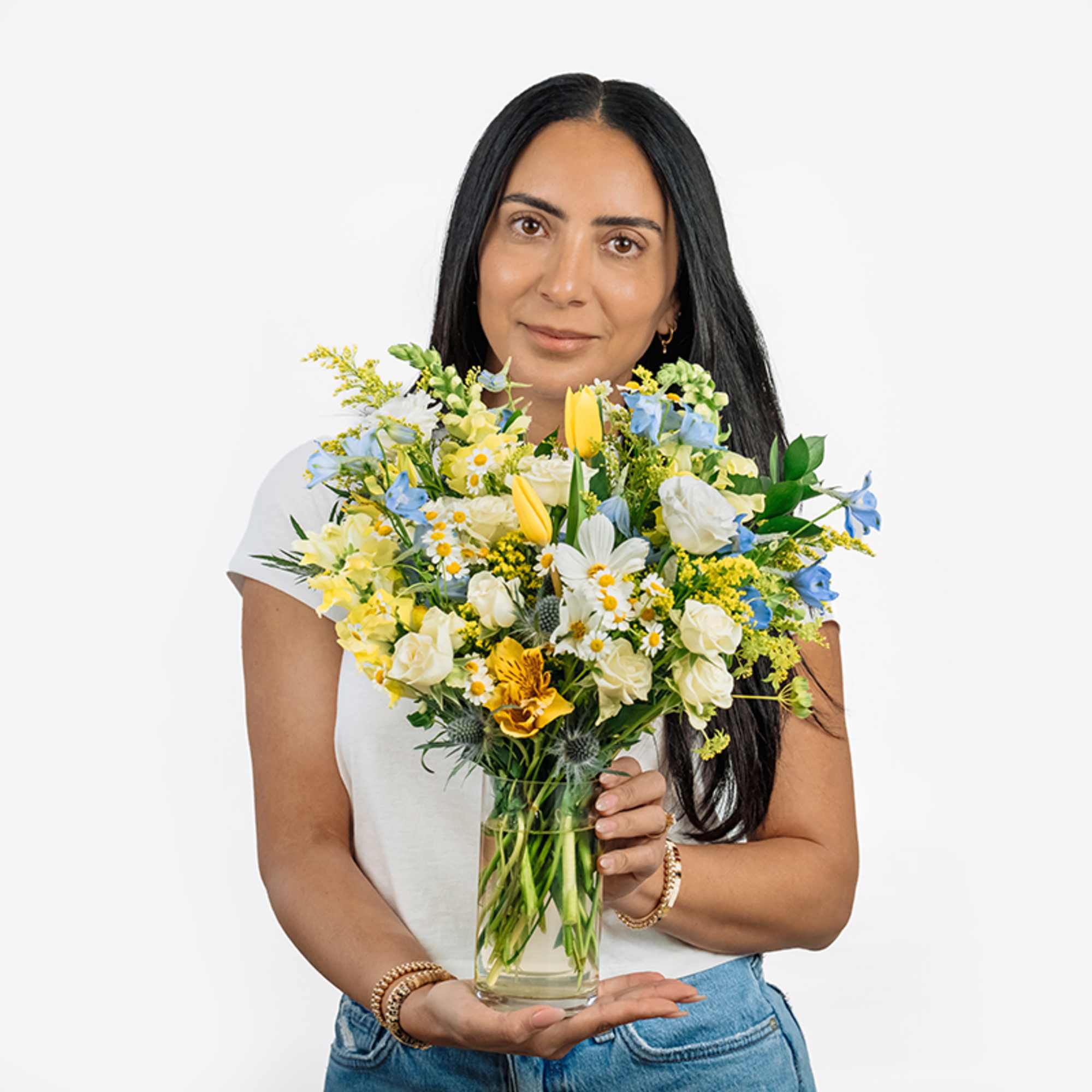 Woman holding a mixed bouquet in a clear glass vase