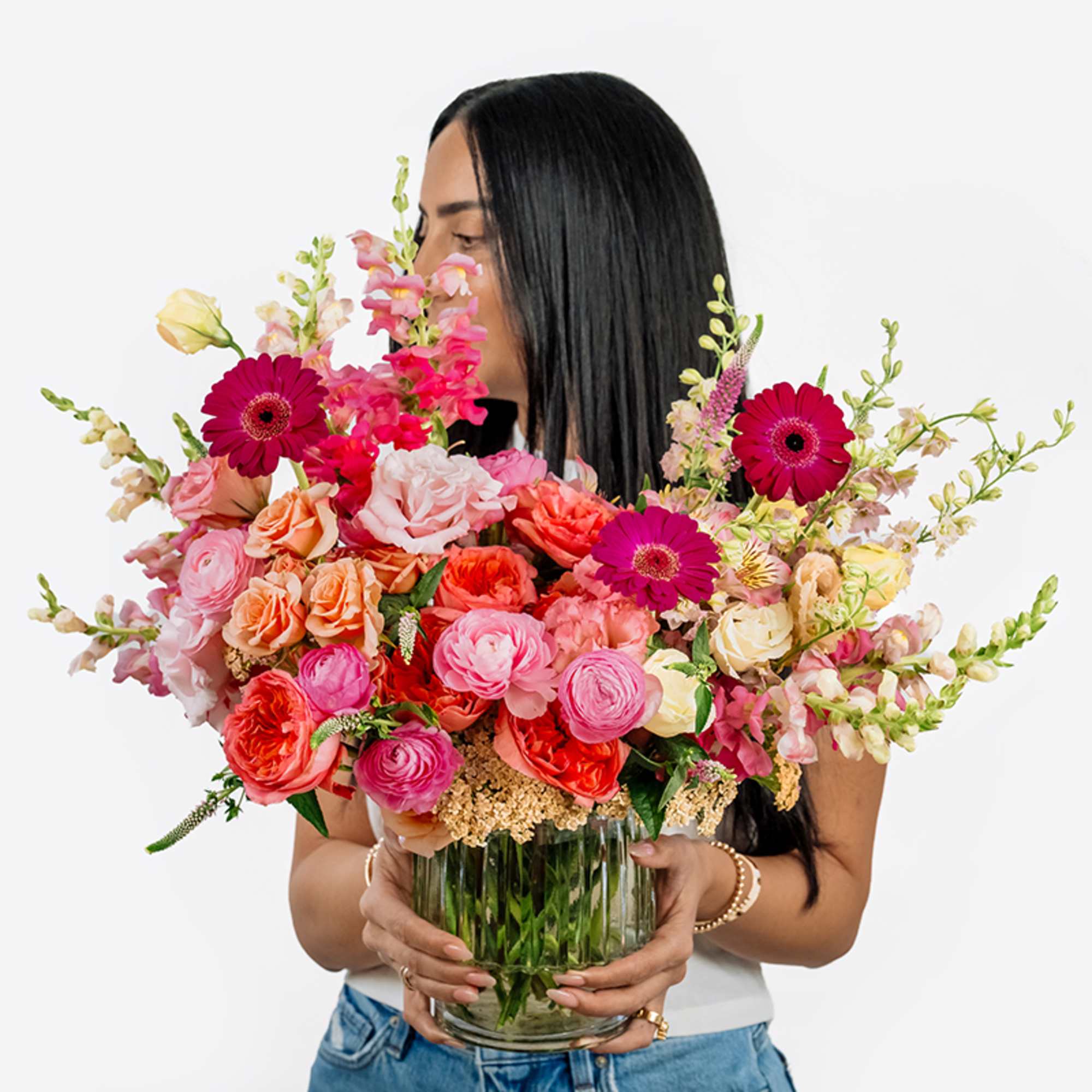 Woman holding a large mixed bouquet in a clear glass vase