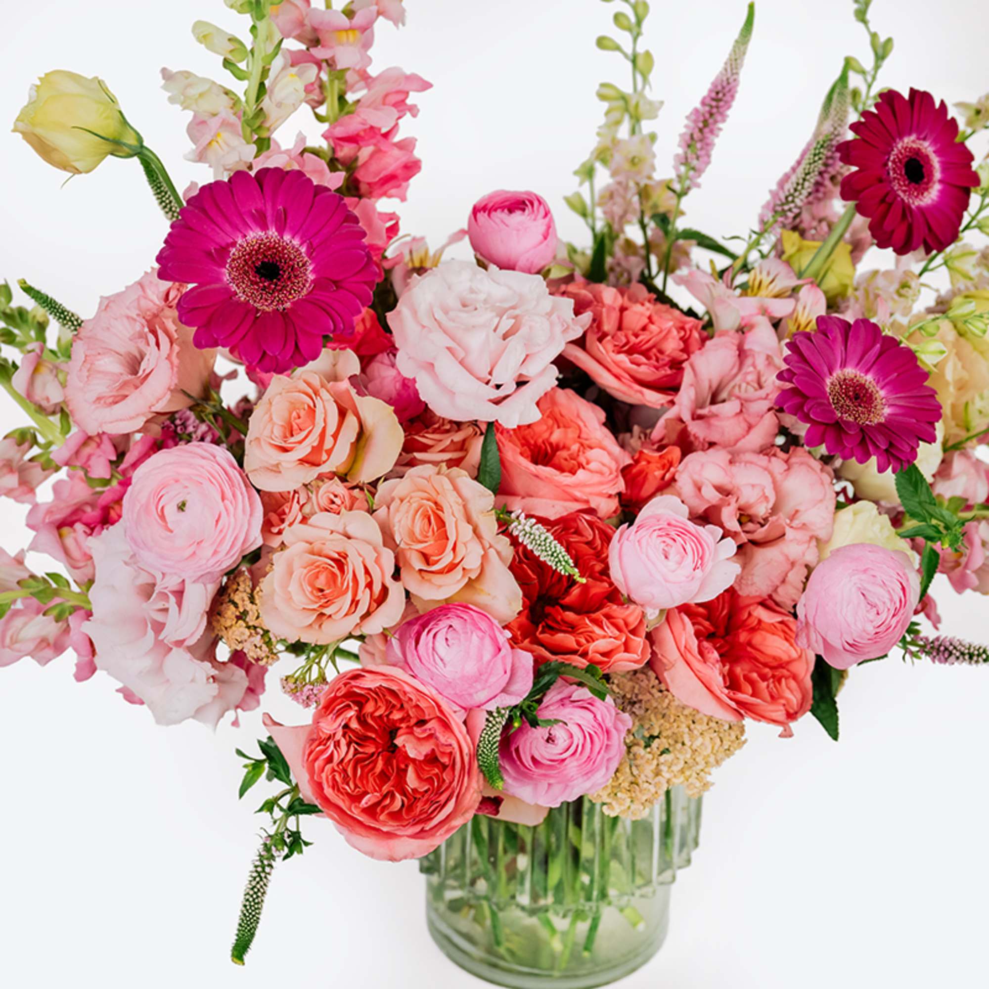 Pink and coral mixed flower arrangement in a clear glass vase