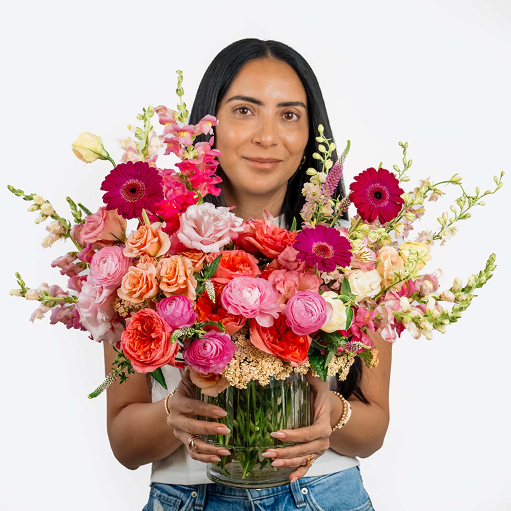 Woman holding a large mixed bouquet in a glass vase
