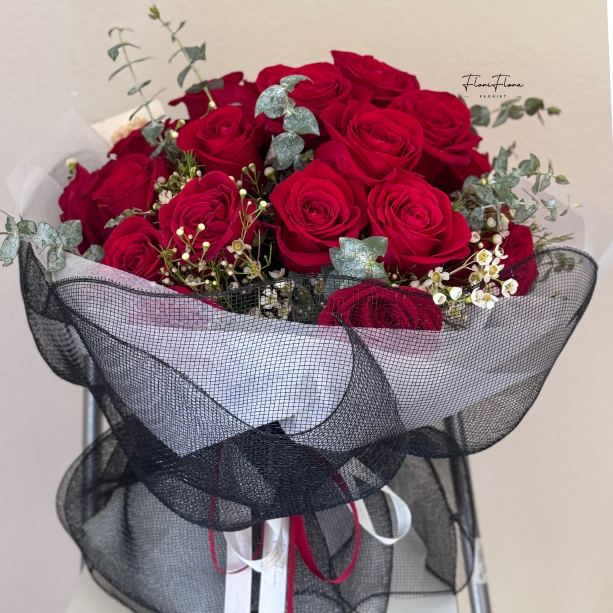 Bouquet of red roses wrapped in black mesh with white accents
