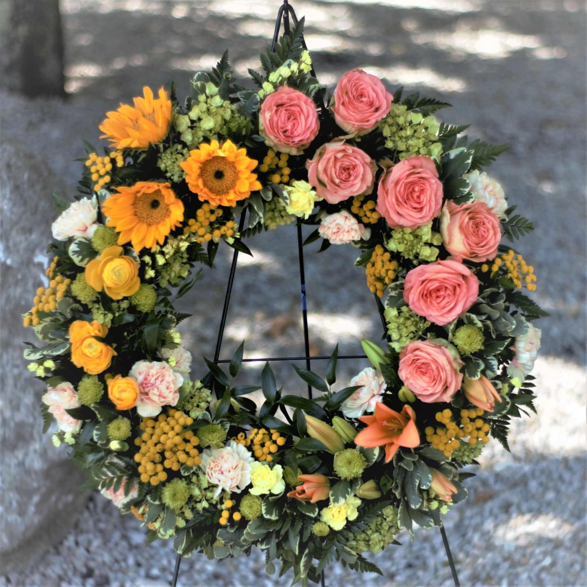 Circular floral wreath with pink roses, orange blooms, and yellow accents