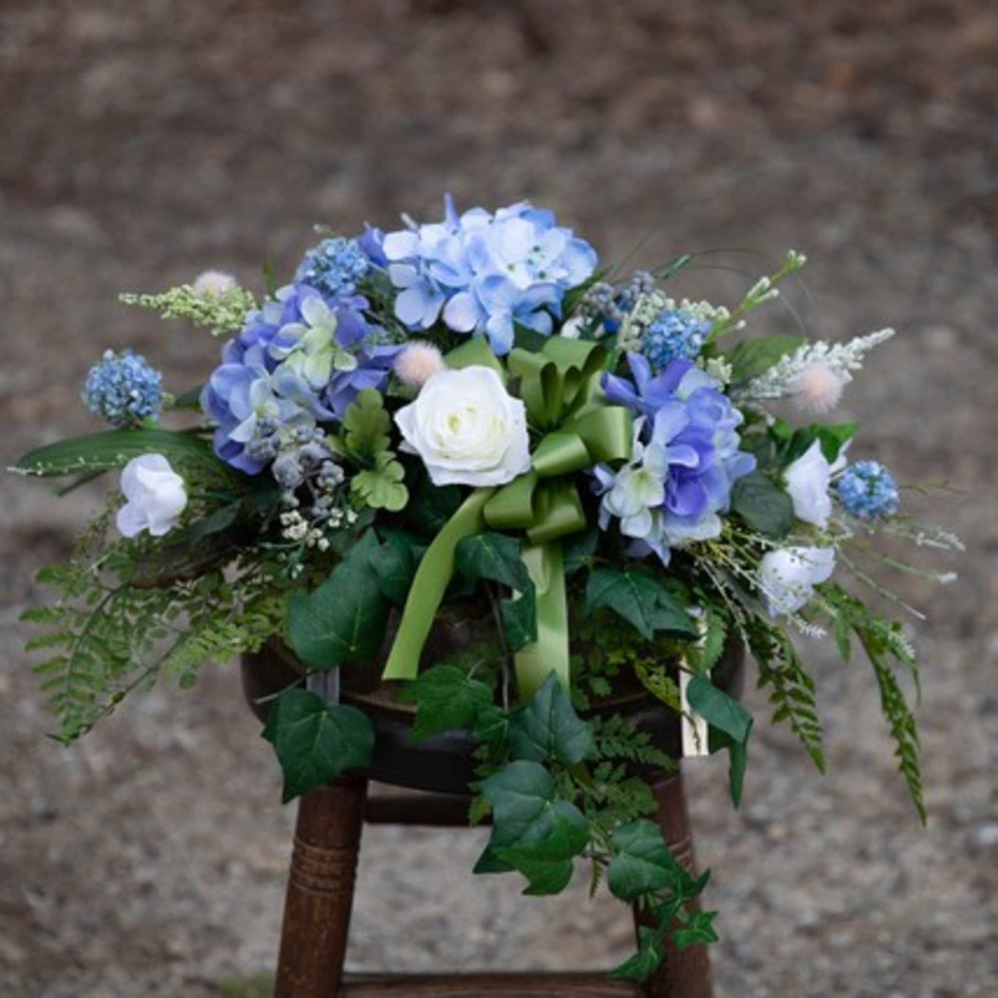 Blue and white floral arrangement with a green ribbon on a stool