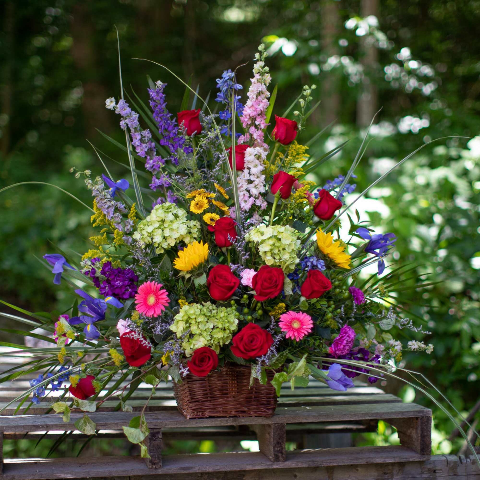 Basket arrangement of red roses and mixed colorful flowers
