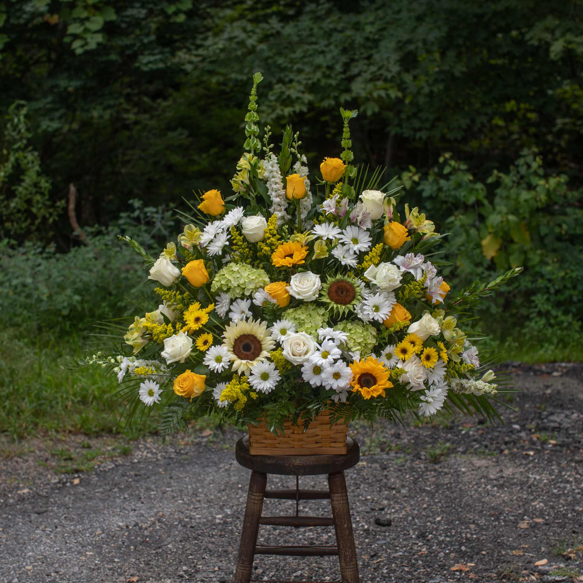 Large yellow and white floral arrangement in a wicker basket