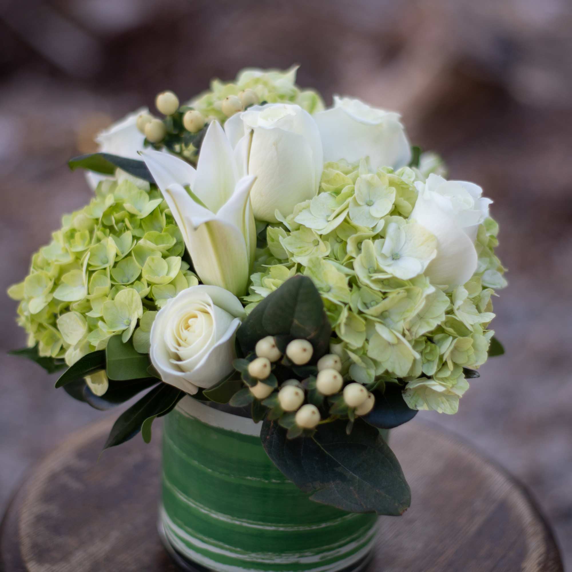 White roses and lilies with pale green hydrangeas in a green vase