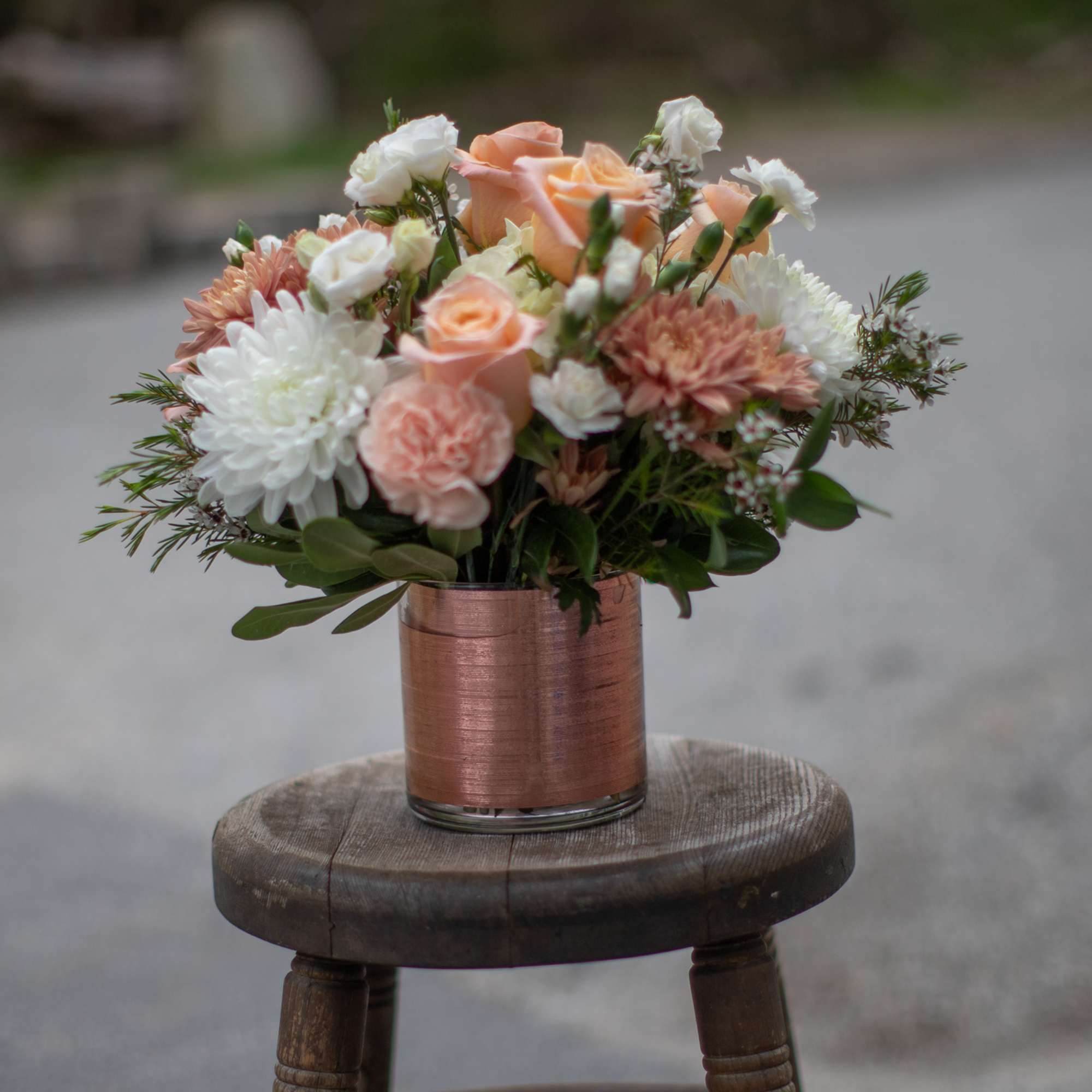 Peach and white flower arrangement in a copper vase
