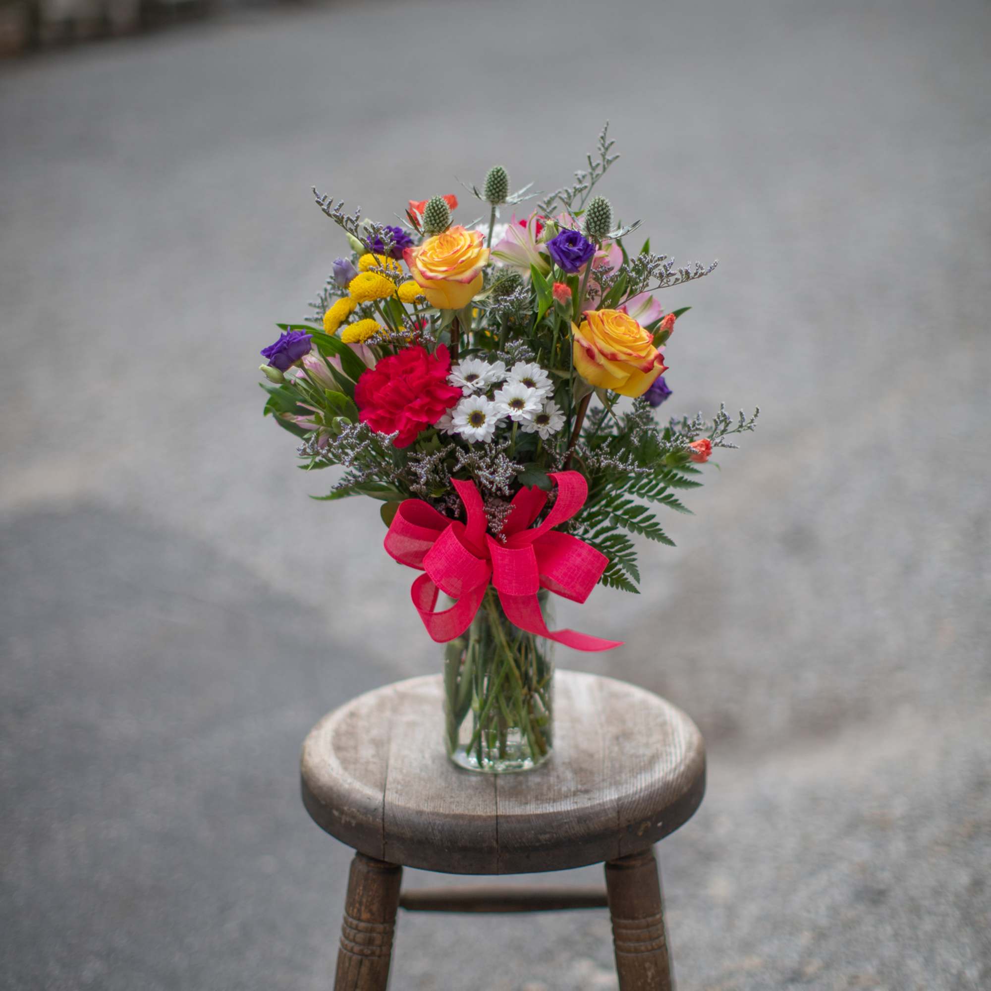Mixed bouquet in a glass vase with a pink ribbon