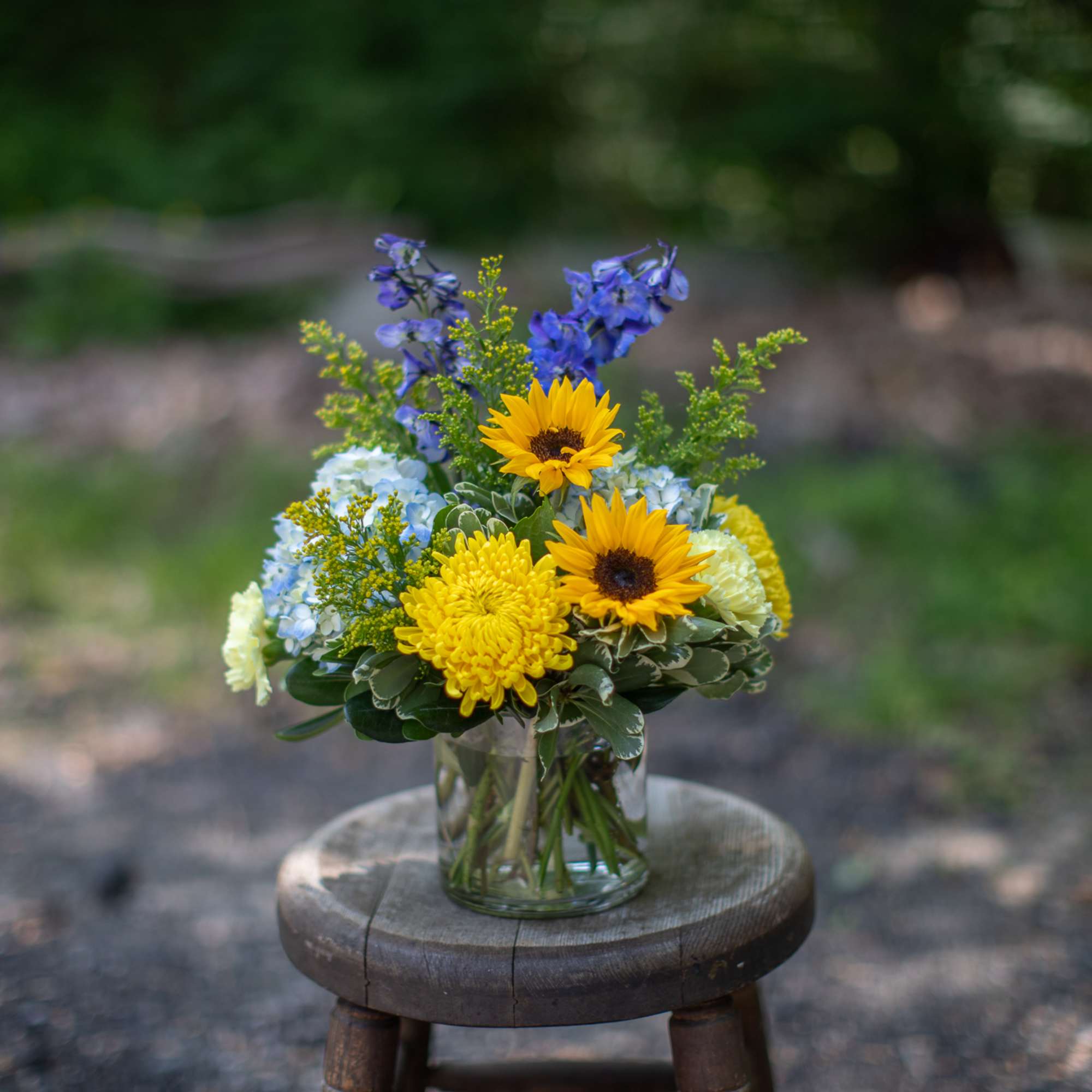 Mixed bouquet in a clear glass vase with yellow sunflowers and blue flowers, photo 2 of 2